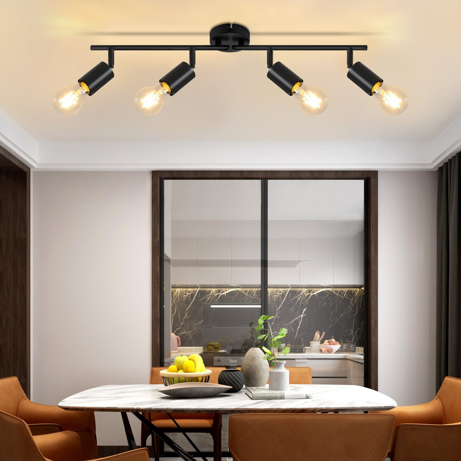 Czarna lampa szynowa z czterema żarówkami nad stołem jadalnym.