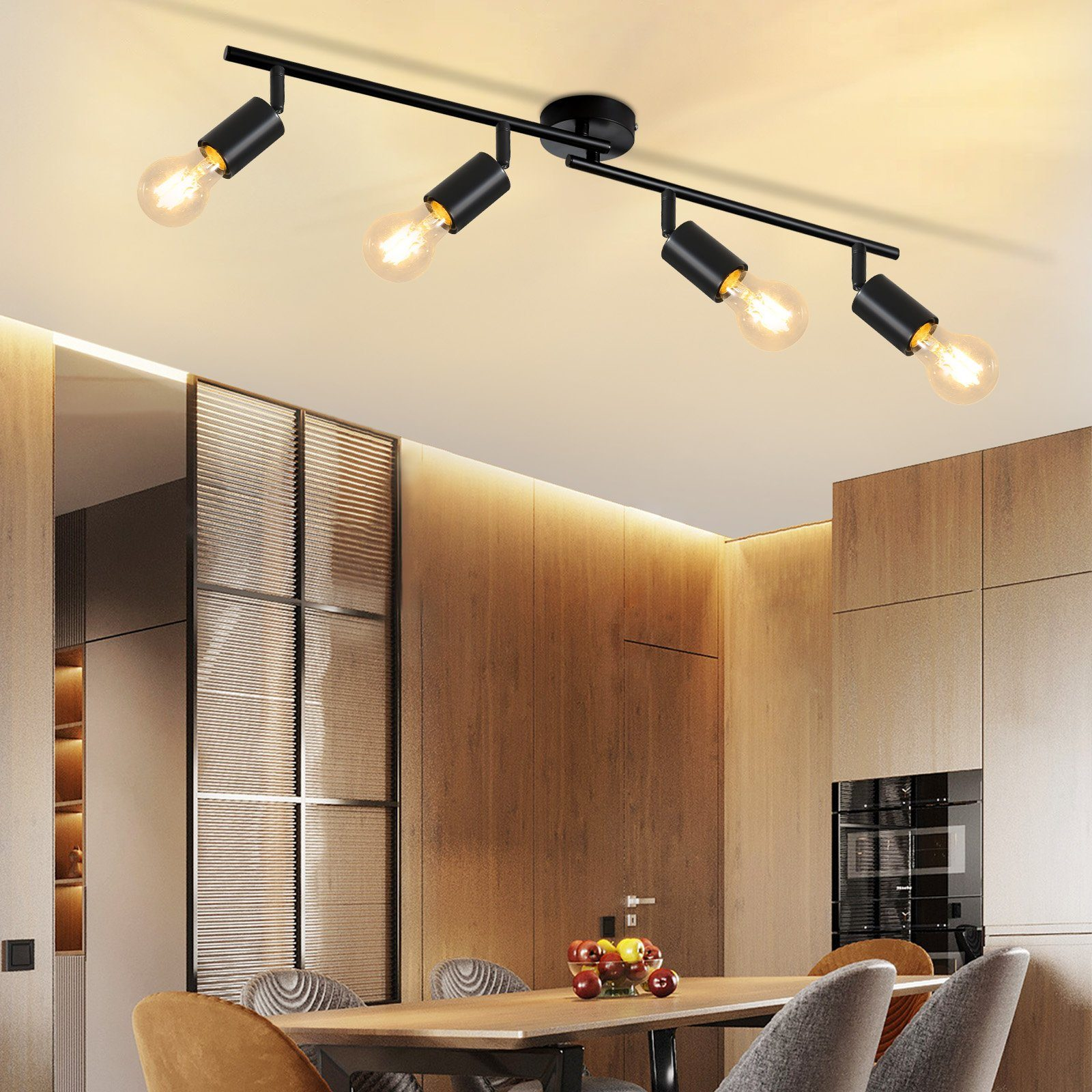 Lampa sufitowa z czterema czarnymi reflektorami z żarówkami. Drewniane panele w tle.