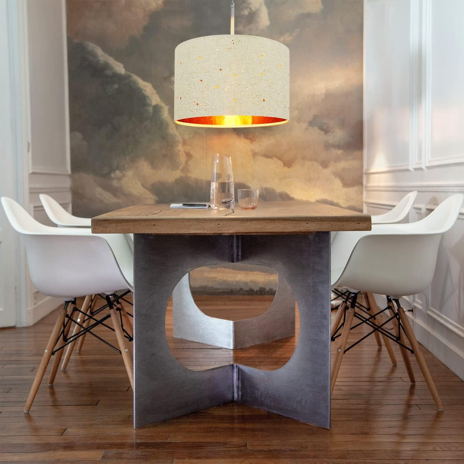 Jadalnia z drewnianym stołem, białymi krzesłami i lampą wiszącą w kształcie gwiazd.