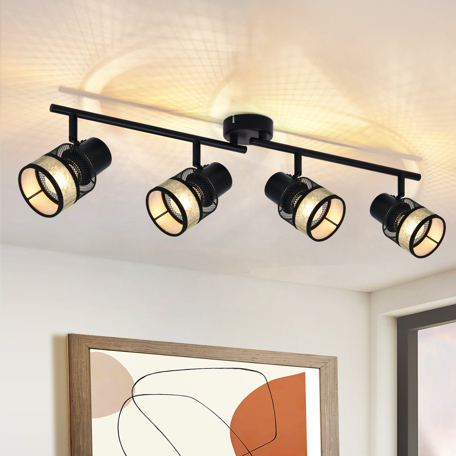 Cztery czarne reflektory zamontowane na czarnym drążku. Światła są cylindryczne i skierowane w dół. Sufit jest biały.