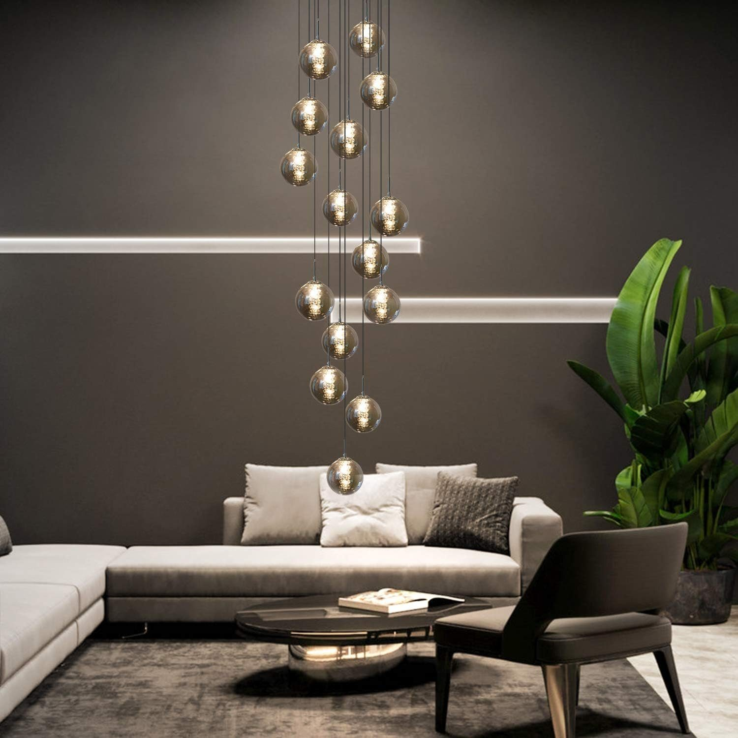 Nowoczesny salon z wiszącym żyrandolem, sofą i rośliną.