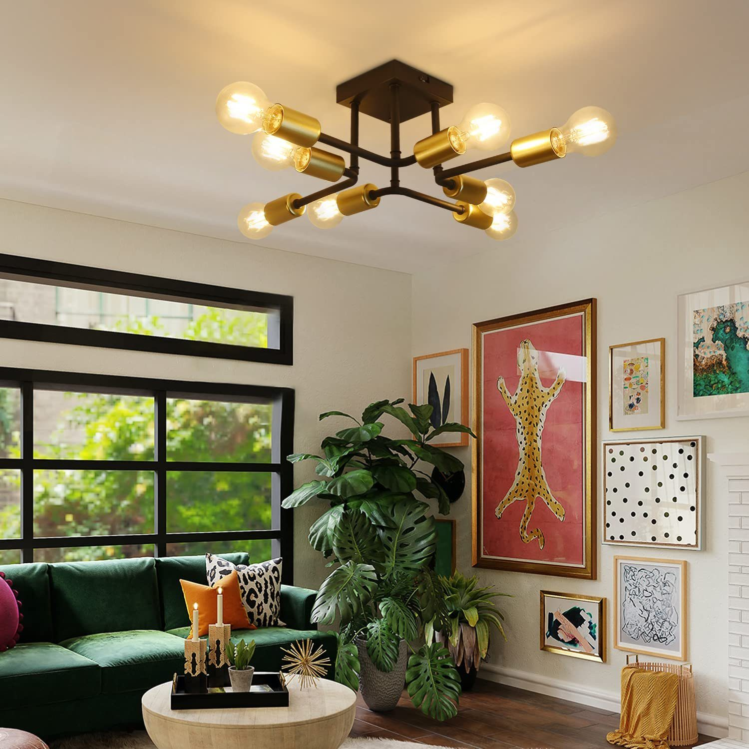 Salon oświetlony żyrandolem z wieloma żarówkami. Różne kolorowe oprawione obrazy i rośliny.