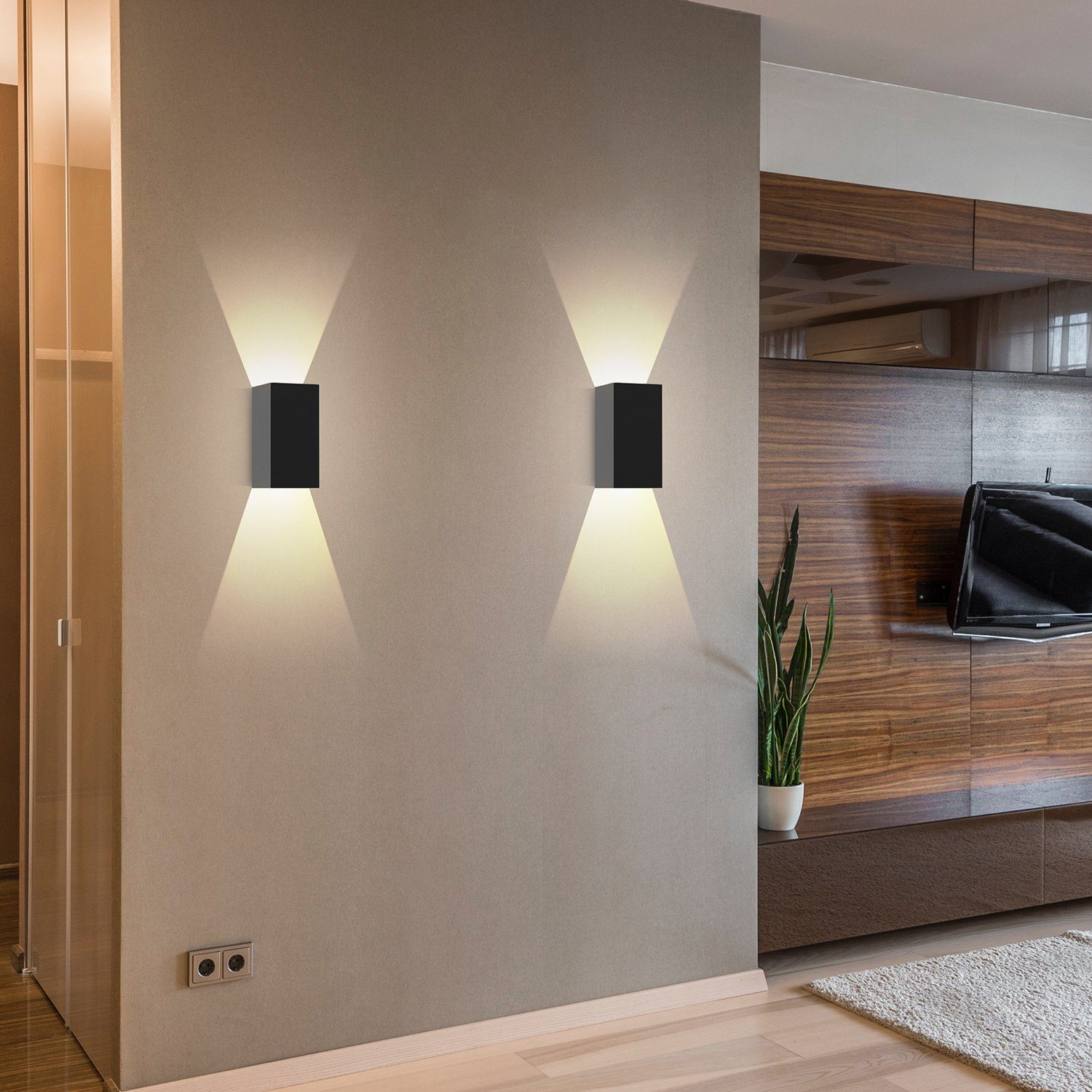 Dwa czarne kinkiety, każdy emitujący światło w górę i w dół. Zamontowane na jasnobeżowej ścianie.