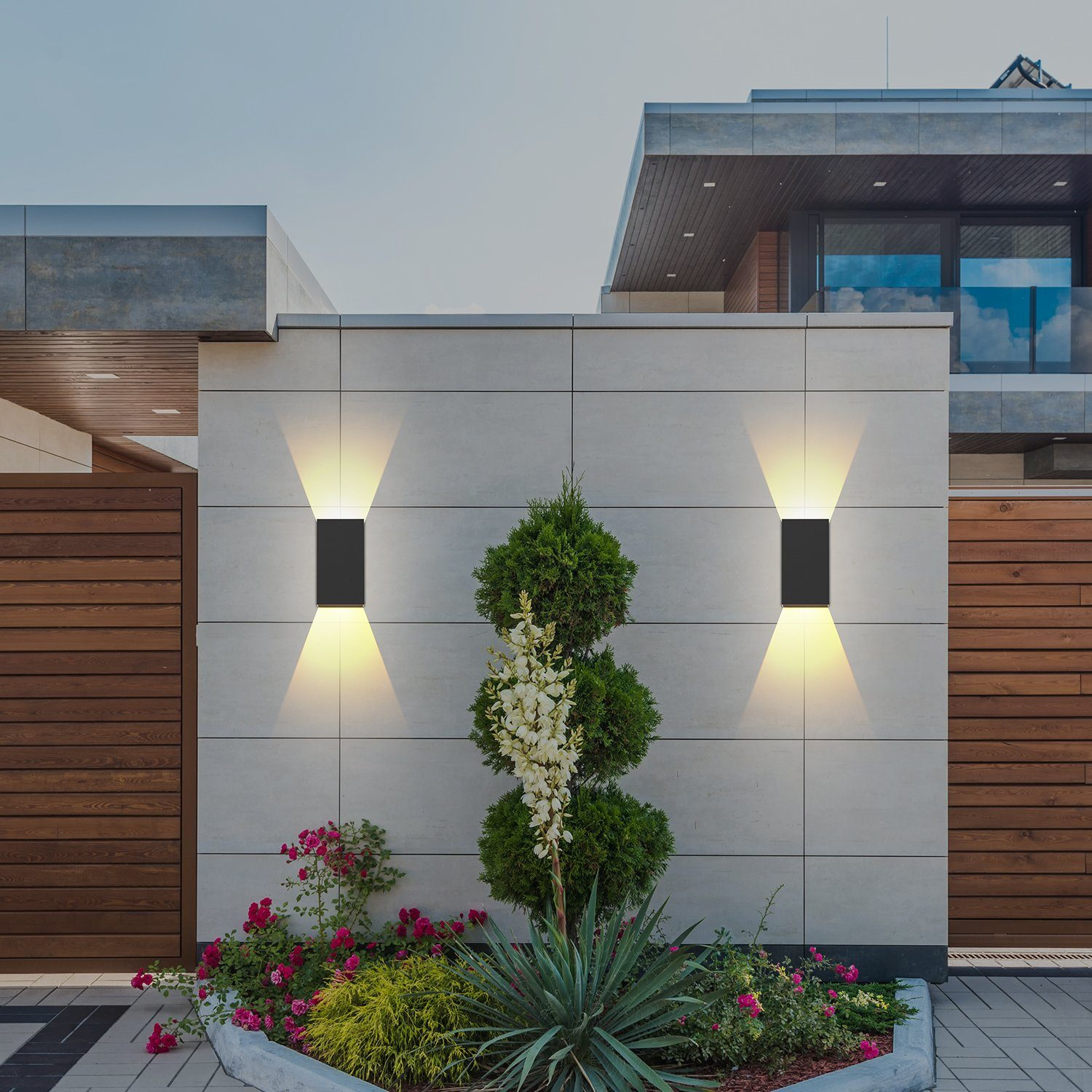 Nowoczesny wygląd domu z lampami ściennymi. Rośliny i drewniane ogrodzenie w scenie.