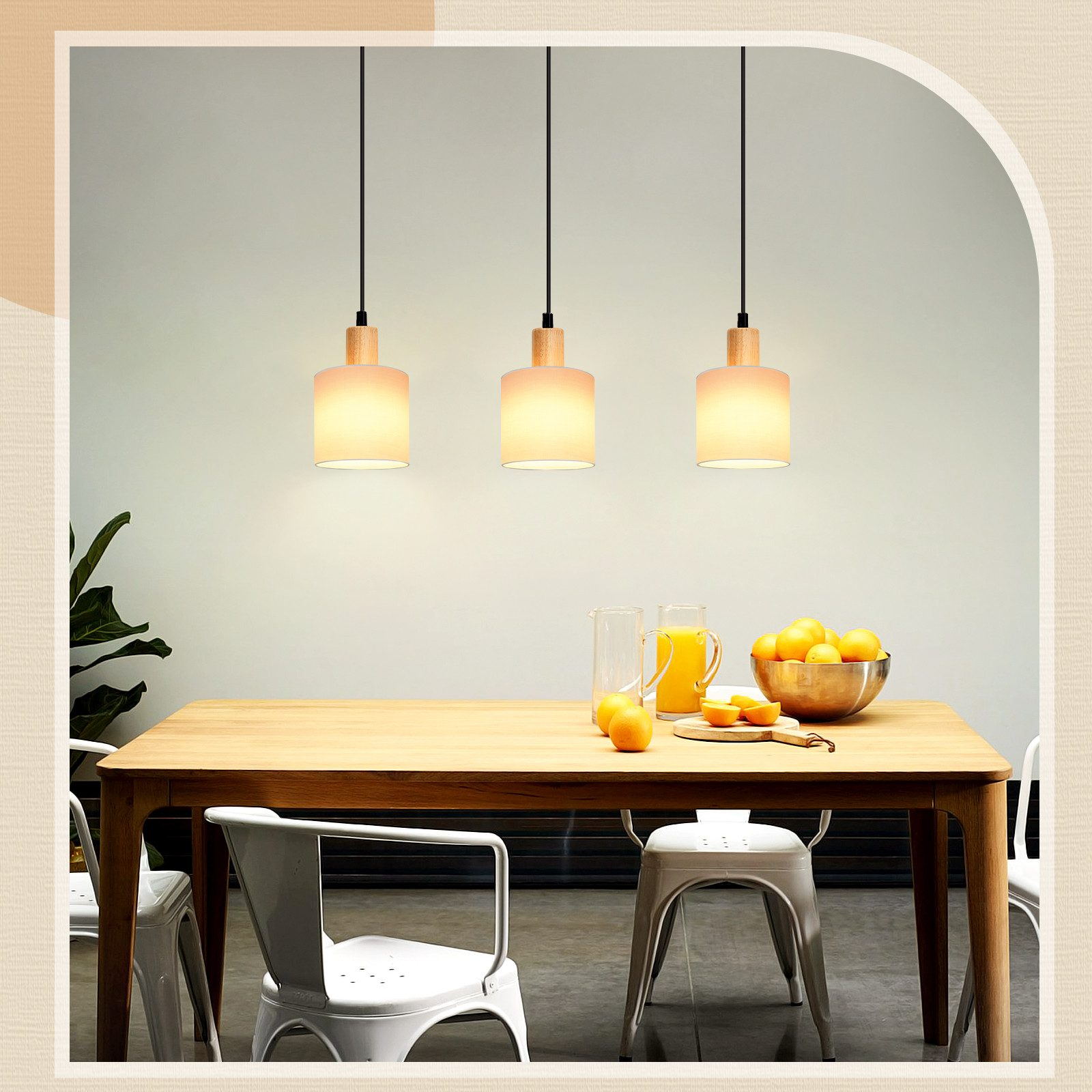 Drei Pendelleuchten über einem Holztisch mit einer Schüssel Orangen und Gläsern. Weißer Hintergrund.