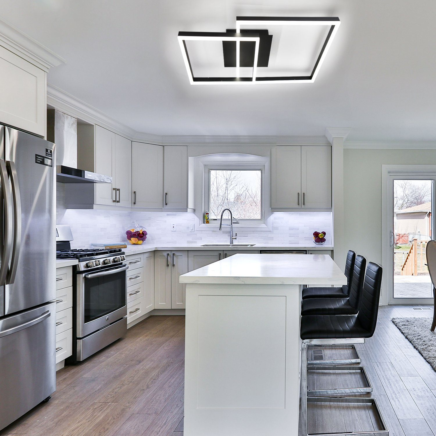 Nowoczesna kuchnia z białymi szafkami, urządzeniami ze stali nierdzewnej i stylową lampą sufitową.