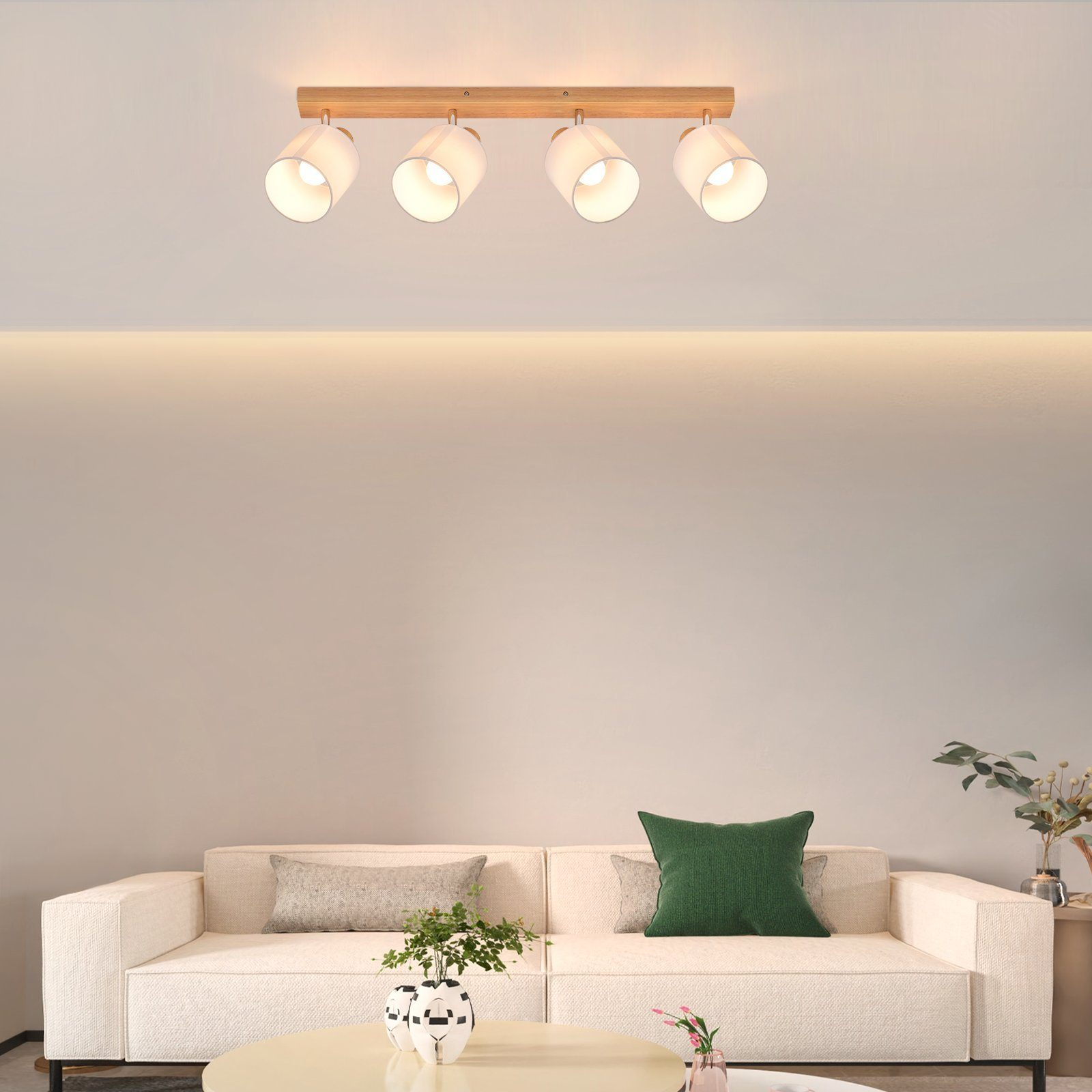 Cztery białe reflektory na drewnianej belce, oświetlające salon z sofą.