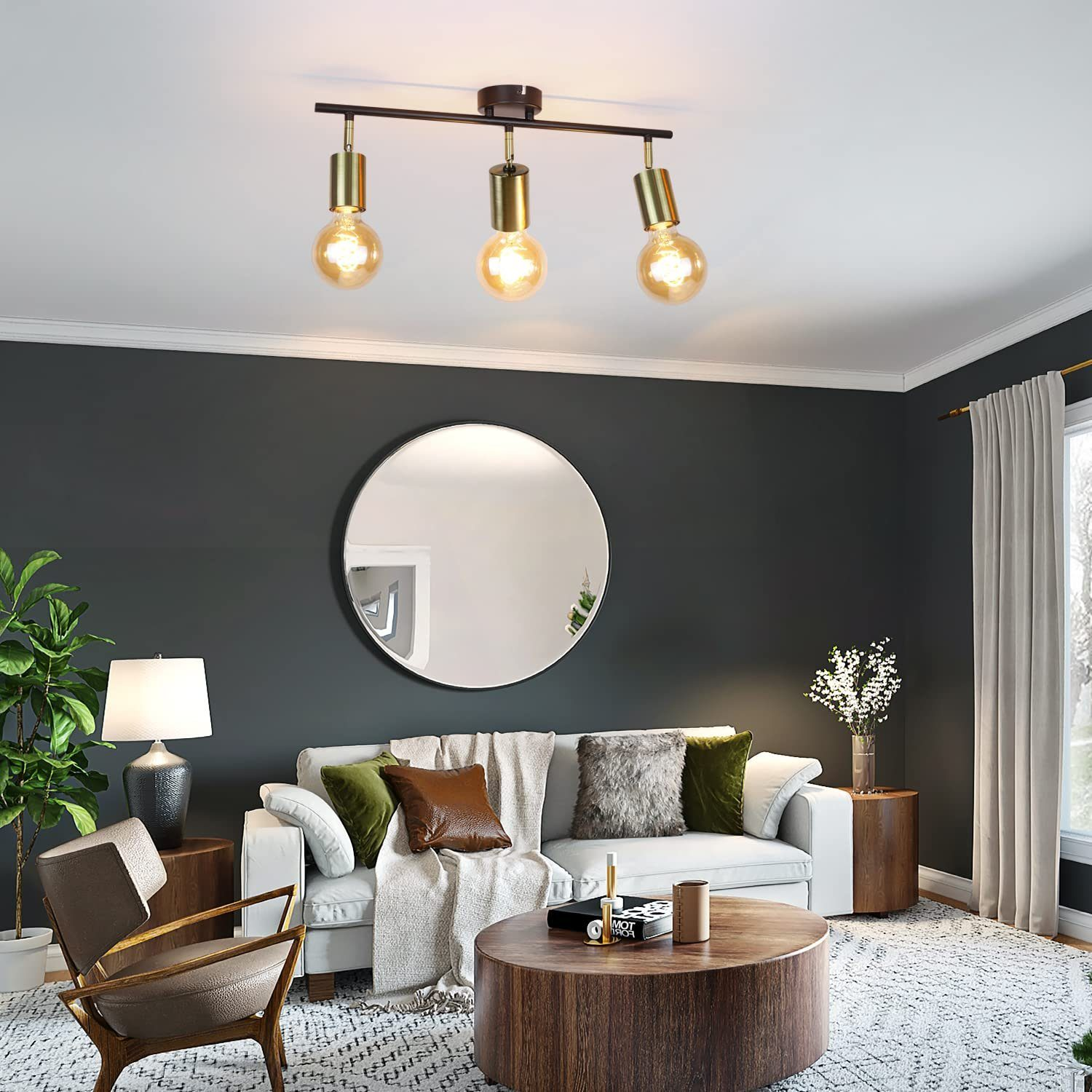 Trzypunktowe oświetlenie szynowe. Pokój ma białą sofę, okrągły stolik kawowy i duże lustro.