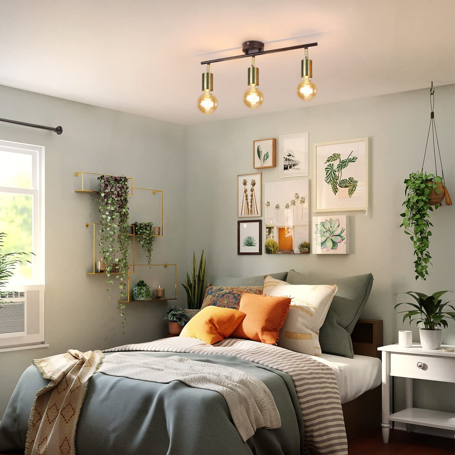 Sypialnia z trzema lampami wiszącymi. Widoczne są także łóżko, poduszki, grafika i rośliny.