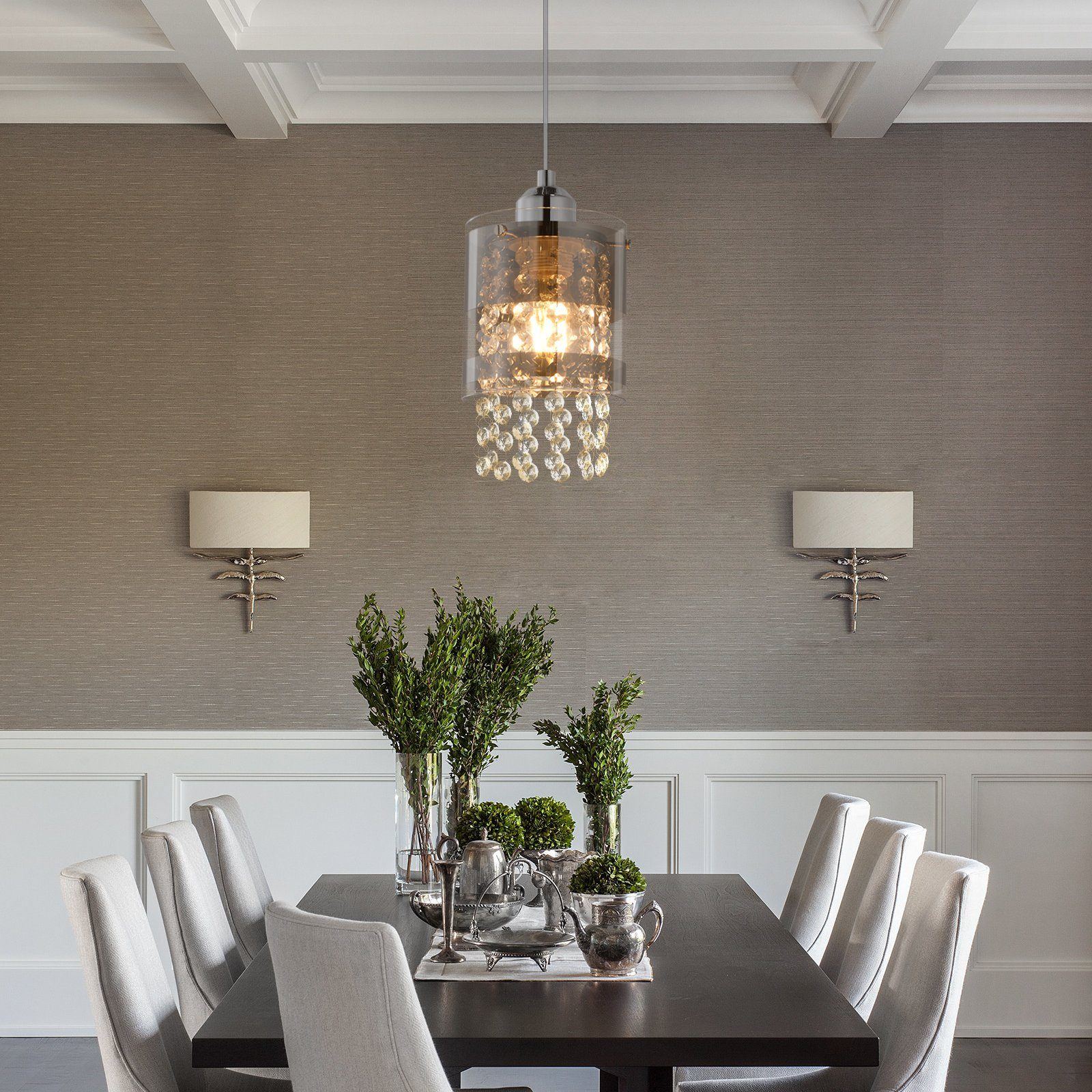 Jadalnia z żyrandolem, dwiema lampami ściennymi, stołem, krzesłami i zielenią.