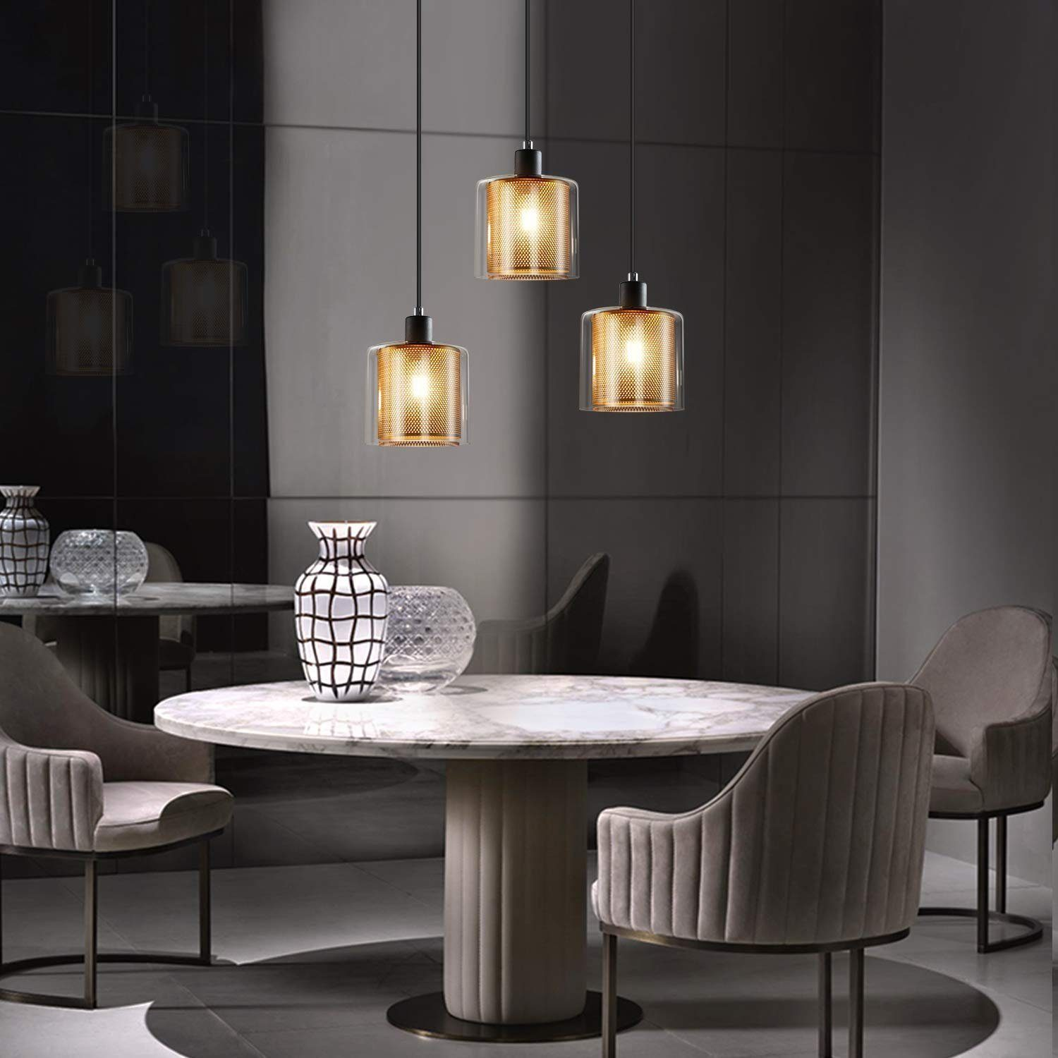 Trzy lampy wiszące z szklanymi kloszami nad marmurowym stołem.
