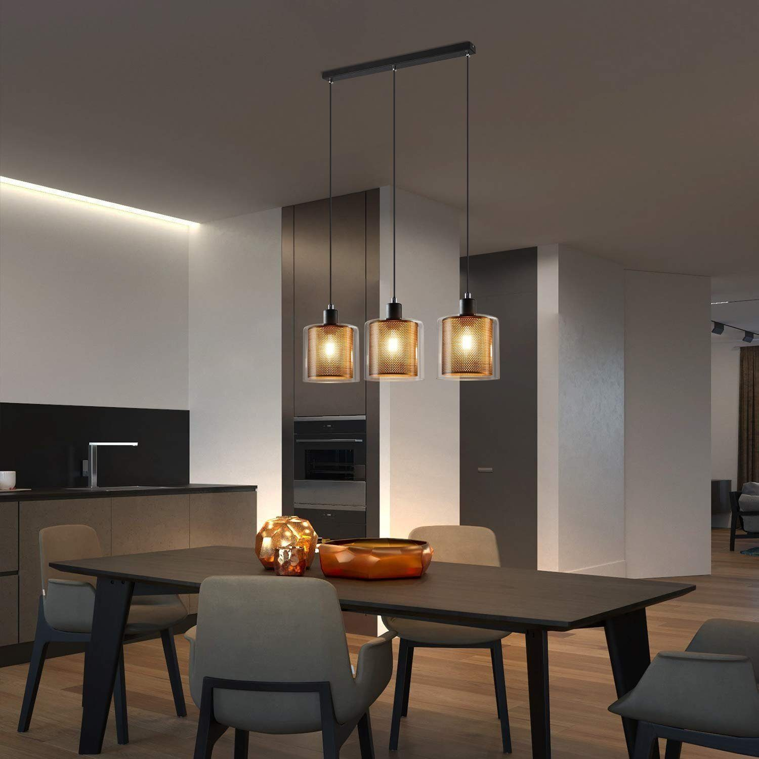 Jadalnia z lampami wiszącymi, ciemnym stołem i kuchnią w tle.