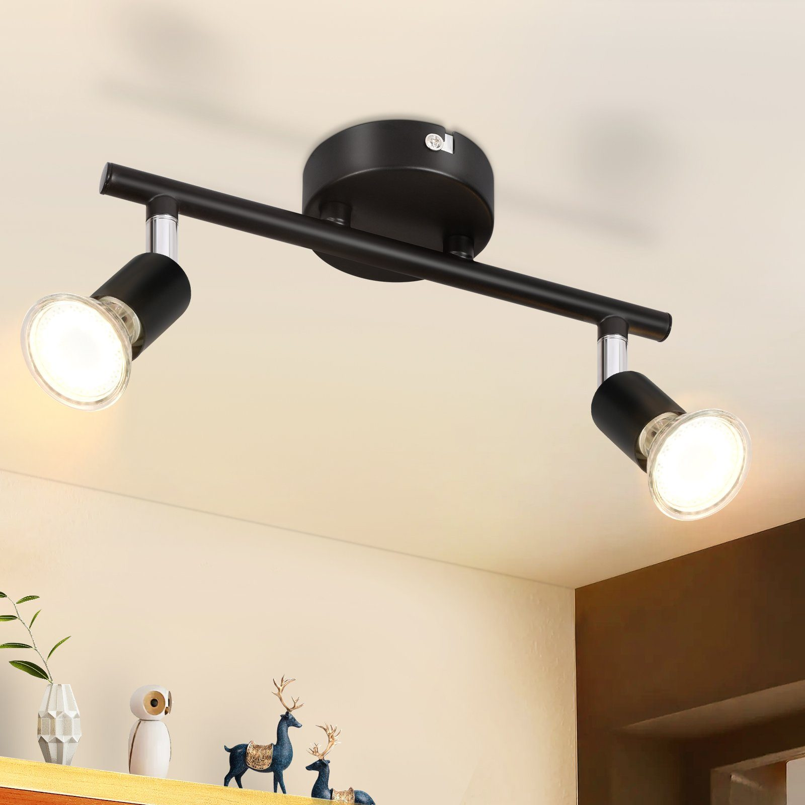 Czarna lampa sufitowa z dwoma światłami, każdy z żarówką. Światło jest włączone.