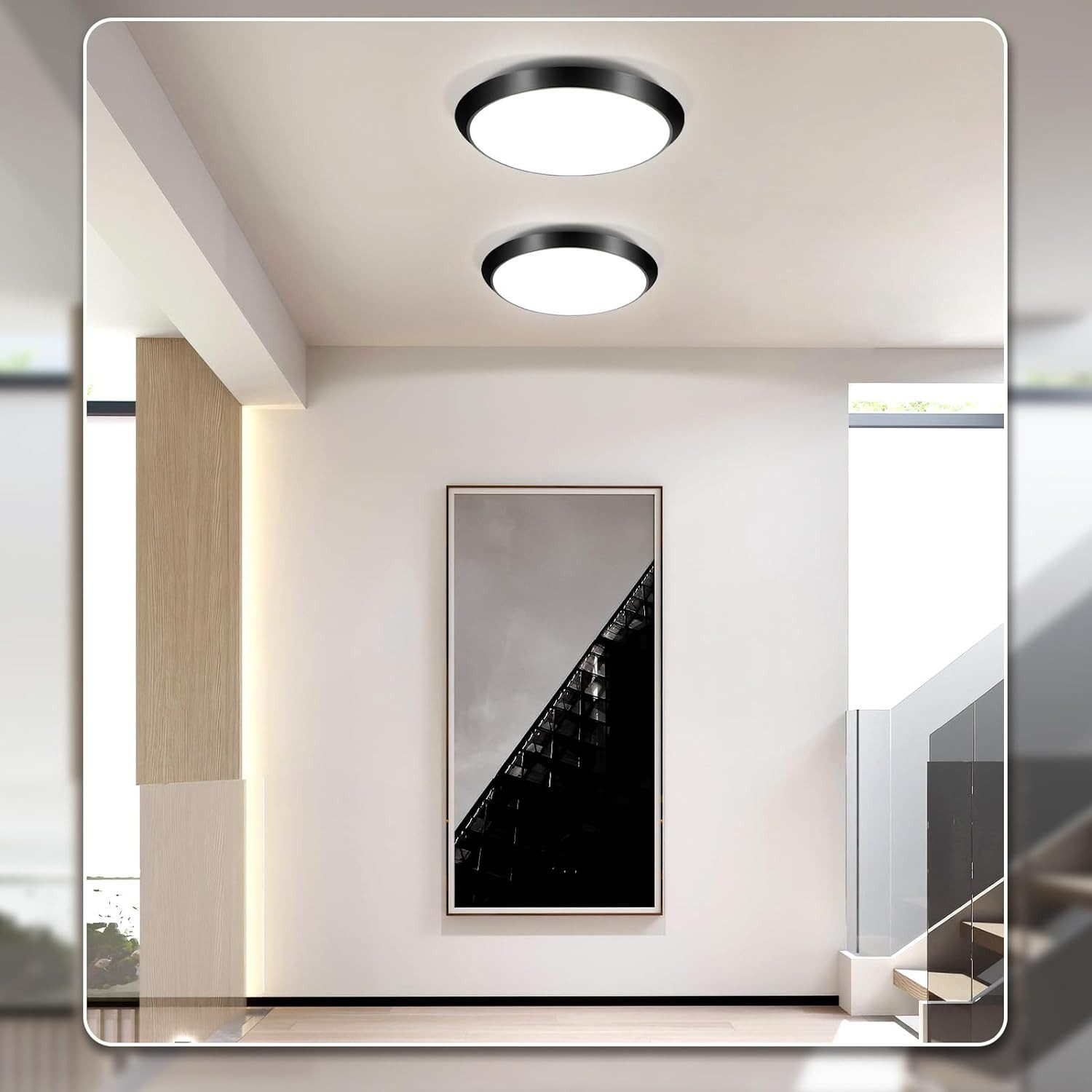 Un corridoio moderno con due luci a soffitto circolari e un'opera d'arte astratta incorniciata sulla parete.