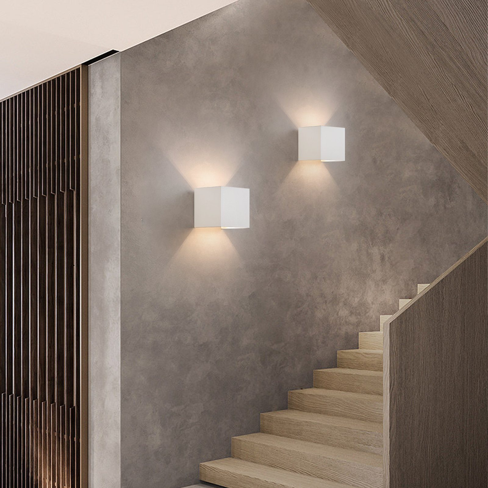 Dwie białe kwadratowe lampy ścienne oświetlają schody. Schody są drewniane.