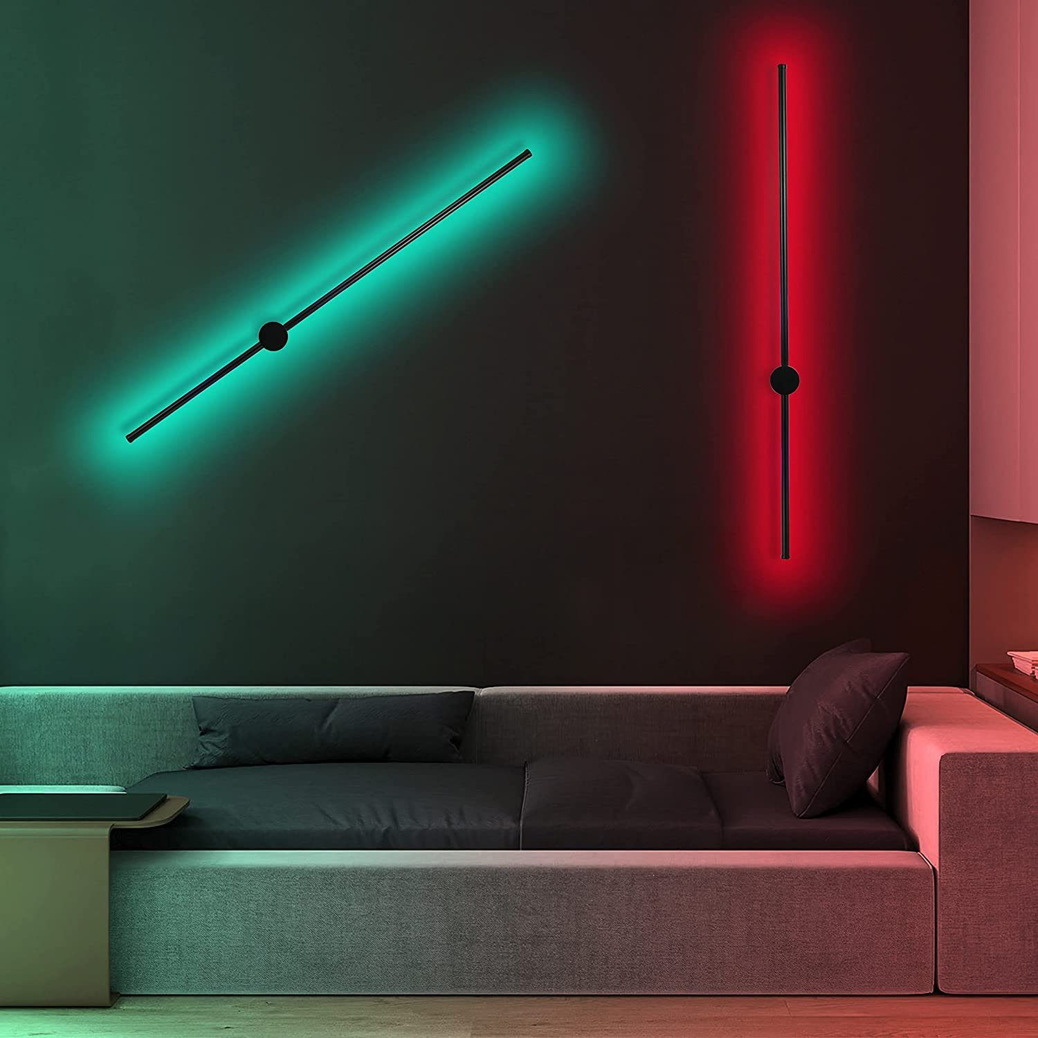 Zwei Wandleuchten, grüne und rote Strahlen an dunkler Wand. Schwarze Leuchten und Sofa.