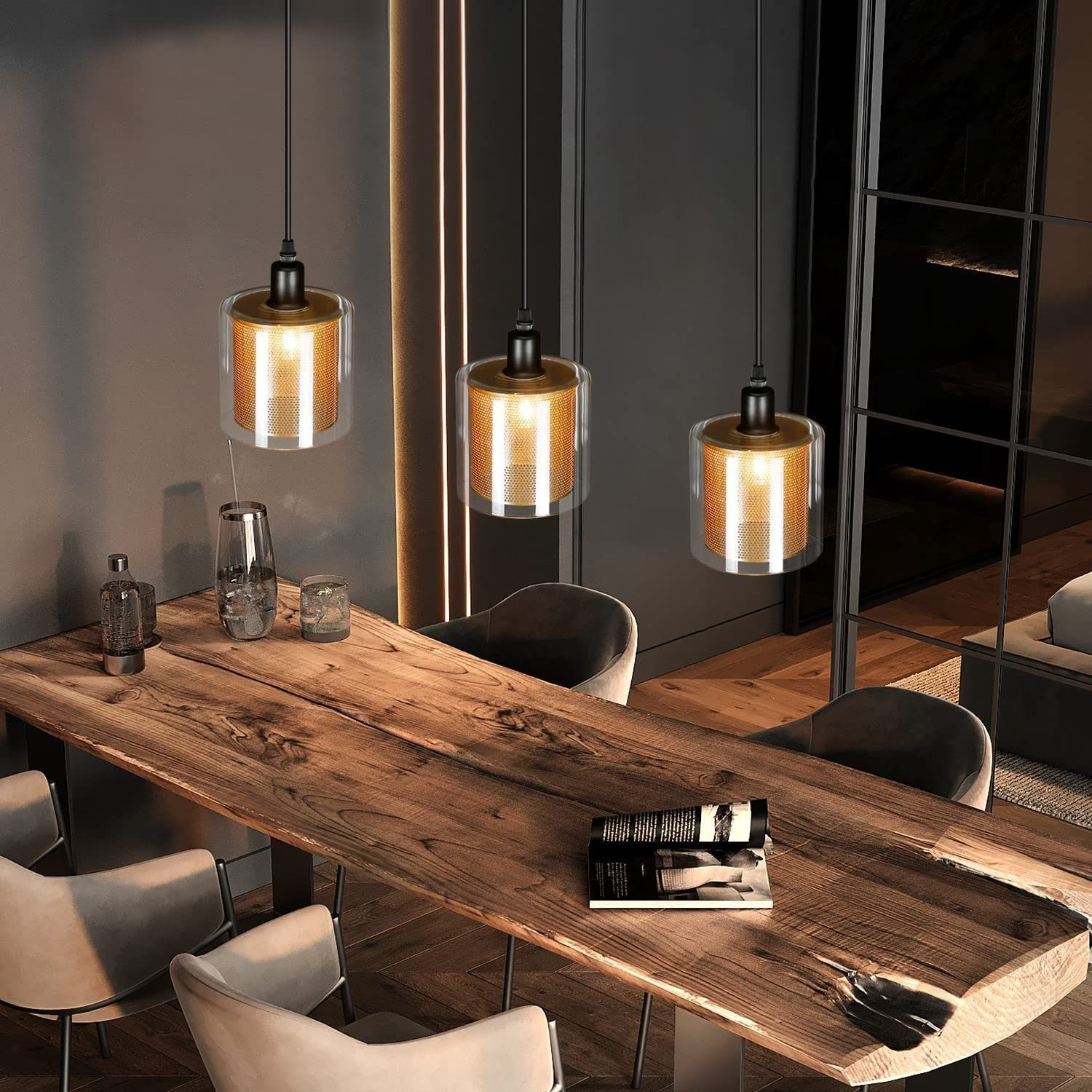 Trzy lampy wiszące nad drewnianym stołem. Lampy mają złote akcenty i szklane klosze.