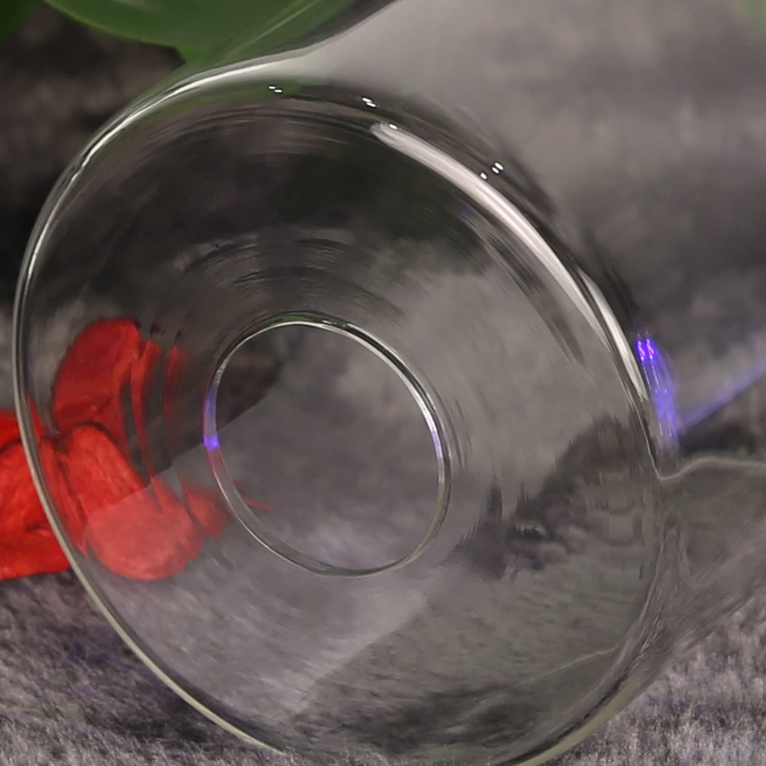 Zbliżenie przezroczystej szklanej butelki. Butelka leży na boku na szarej powierzchni.