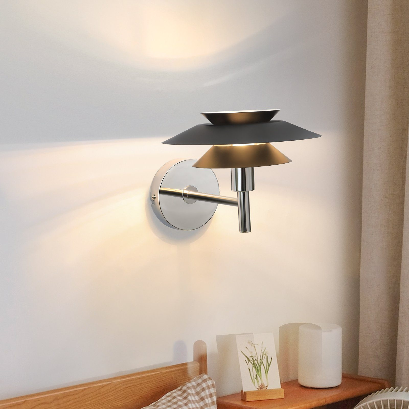 Lampa ścienna z warstwowym kloszem. Lampa jest zamontowana na ścianie obok łóżka i małego stolika.