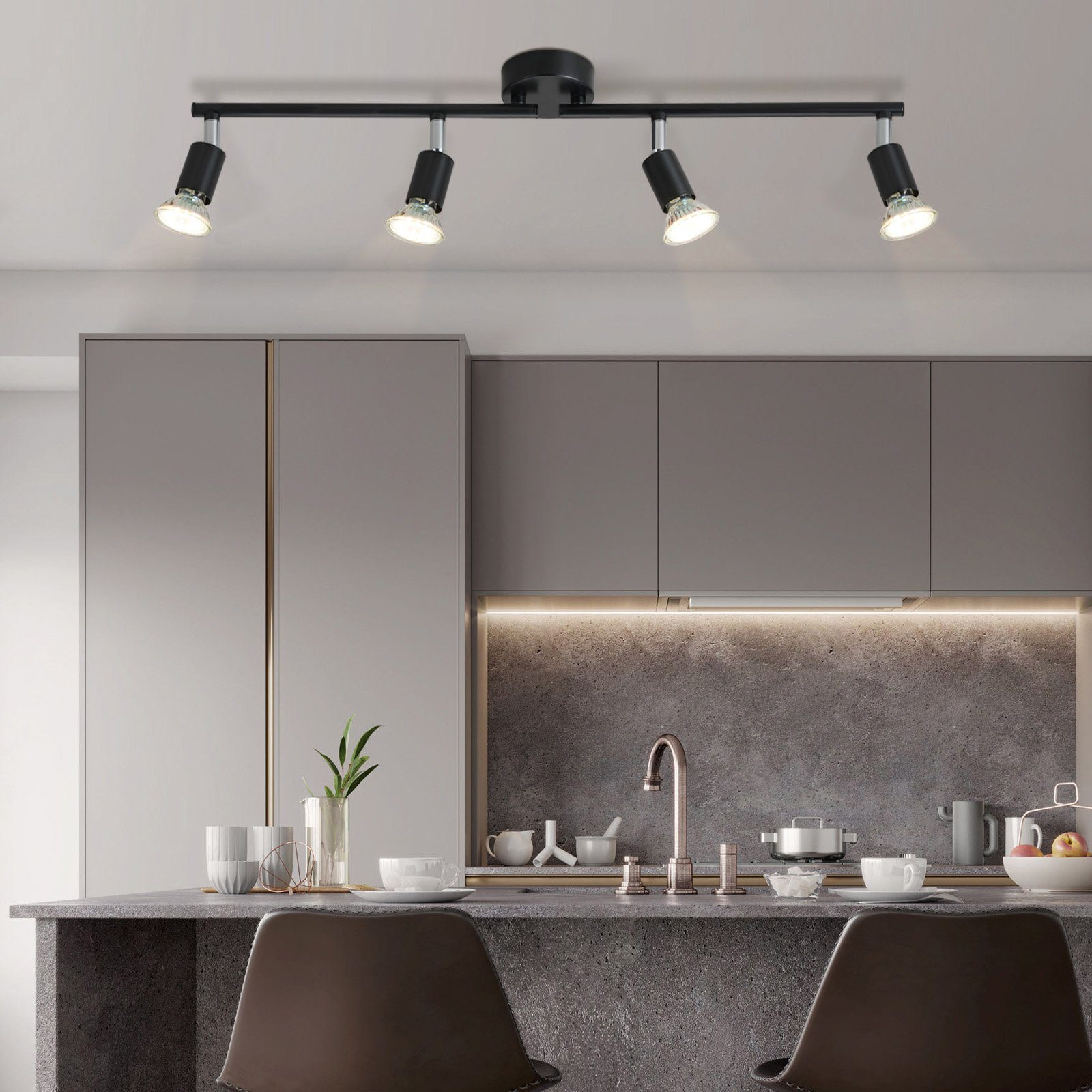 Kuchnia z oświetleniem szynowym. Cztery czarne reflektory są zainstalowane na suficie, oświetlając bar kuchenny.