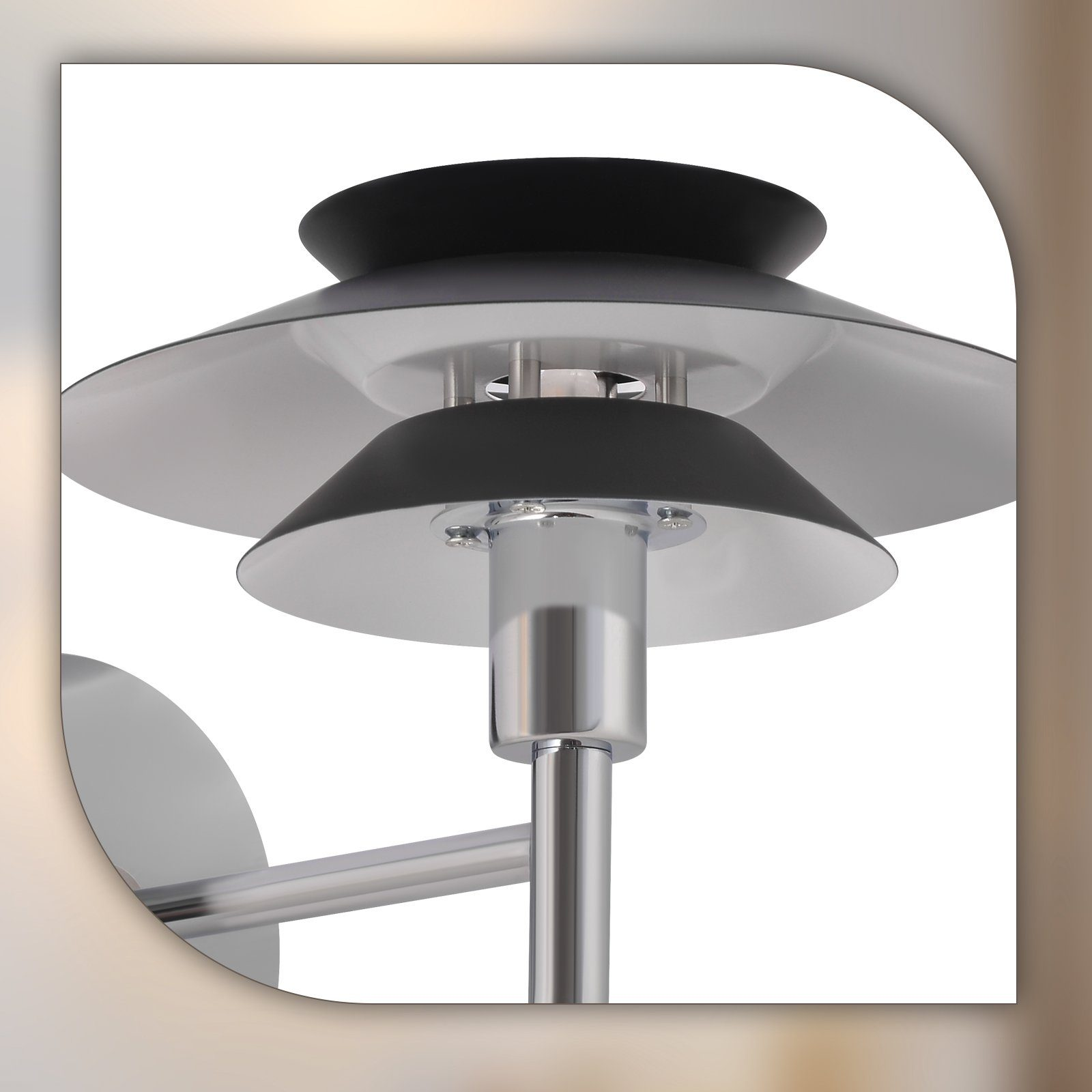 Zbliżenie srebrno-czarnej lampy o warstwowym designie na białym tle.