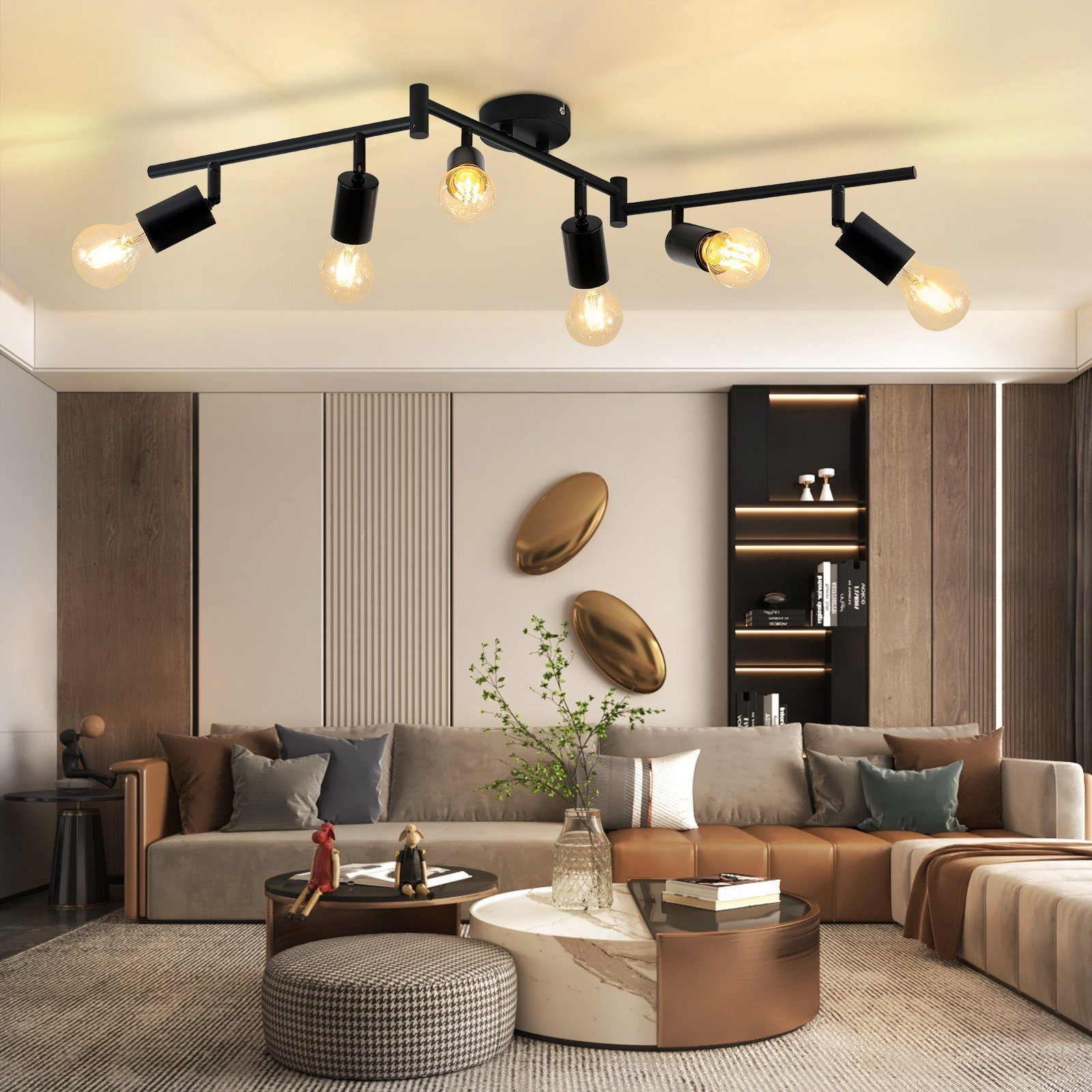 Ein Wohnzimmer mit einer schwarzen Deckenleuchte und mehreren Glühbirnen. Es gibt ein Sofa und einen Couchtisch.