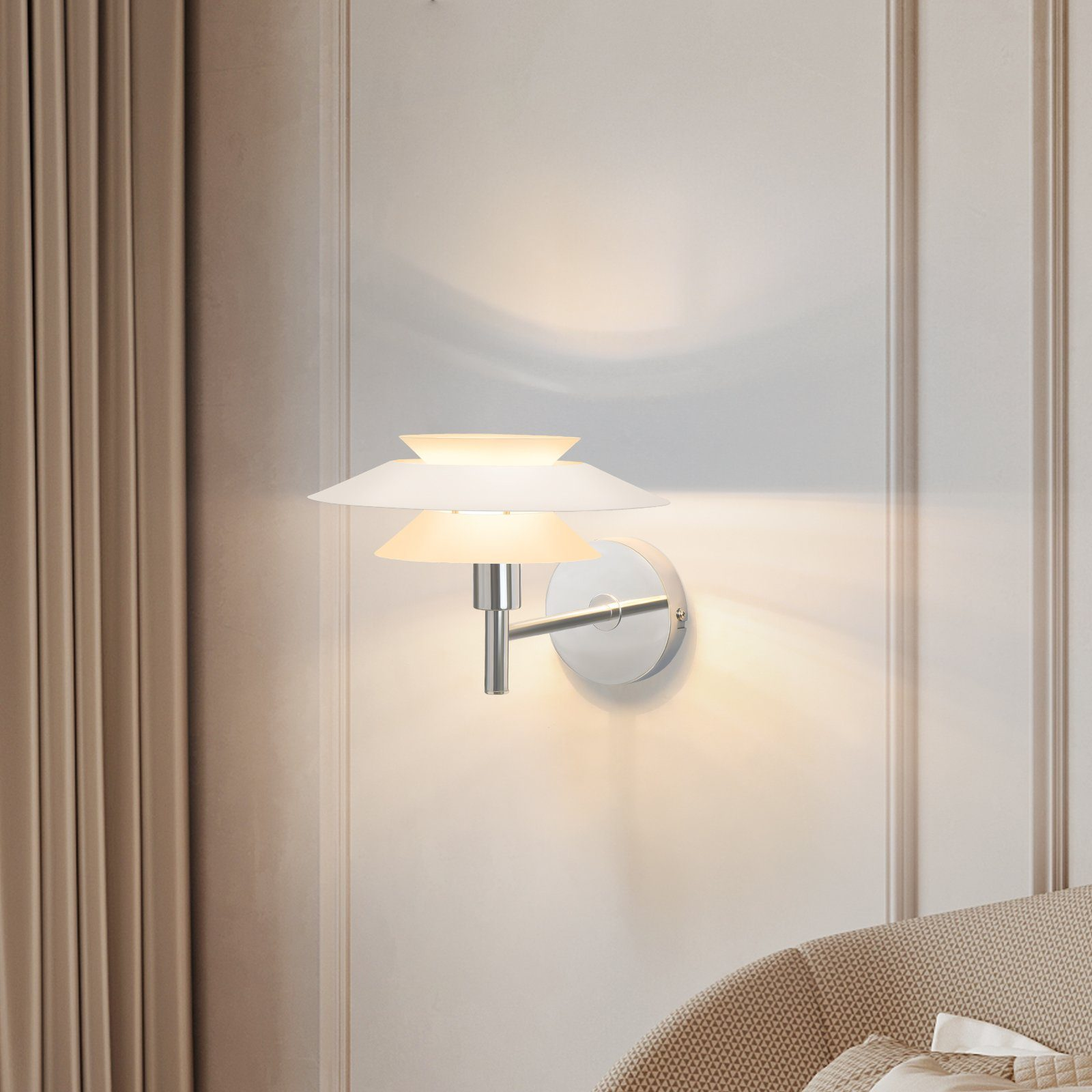 Biała lampa ścienna z trzema warstwowymi kloszami jest zamontowana na białej ścianie.