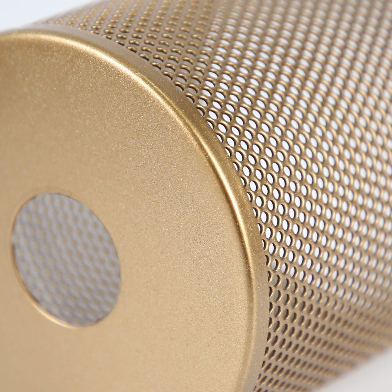 Zbliżenie złotego, perforowanego metalowego cylindra. Cylinder ma wiele małych otworów i zaokrągloną górną krawędź.