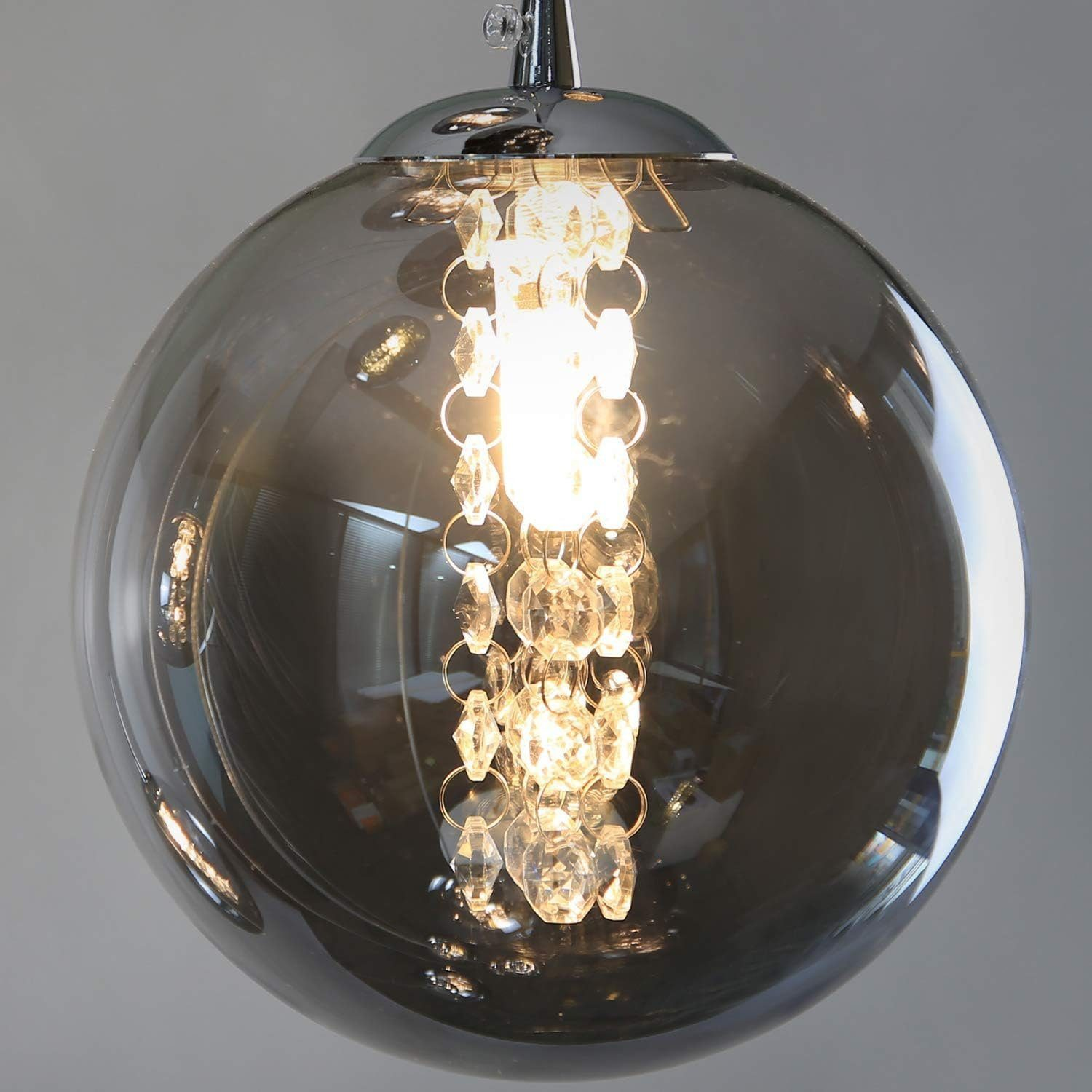 Szara szklana lampa wisząca w kształcie kuli z kryształowymi akcentami. Jasne światło w środku.