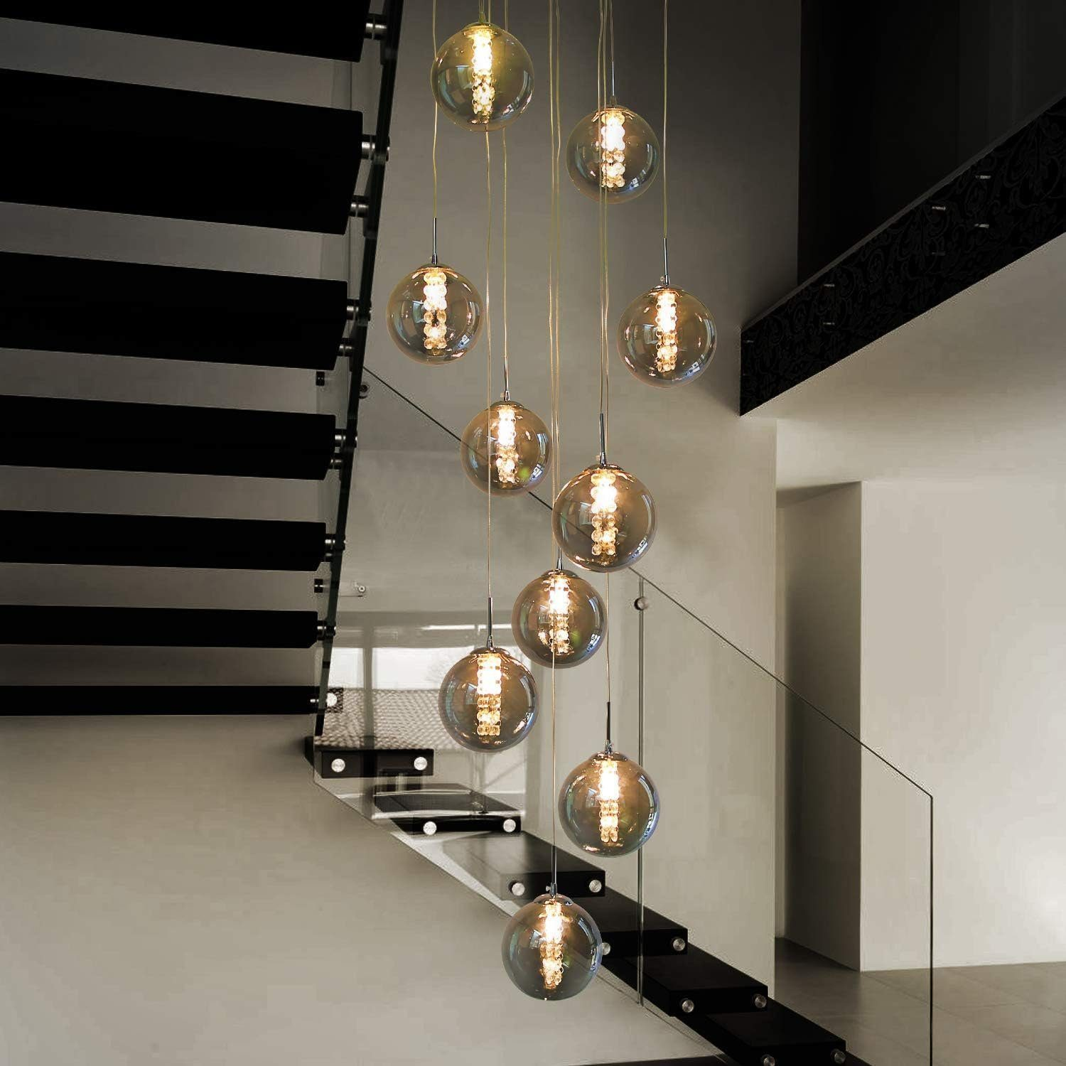 Schody ze szklaną balustradą i wiszącymi lampami kulistymi. Czarno-białe.