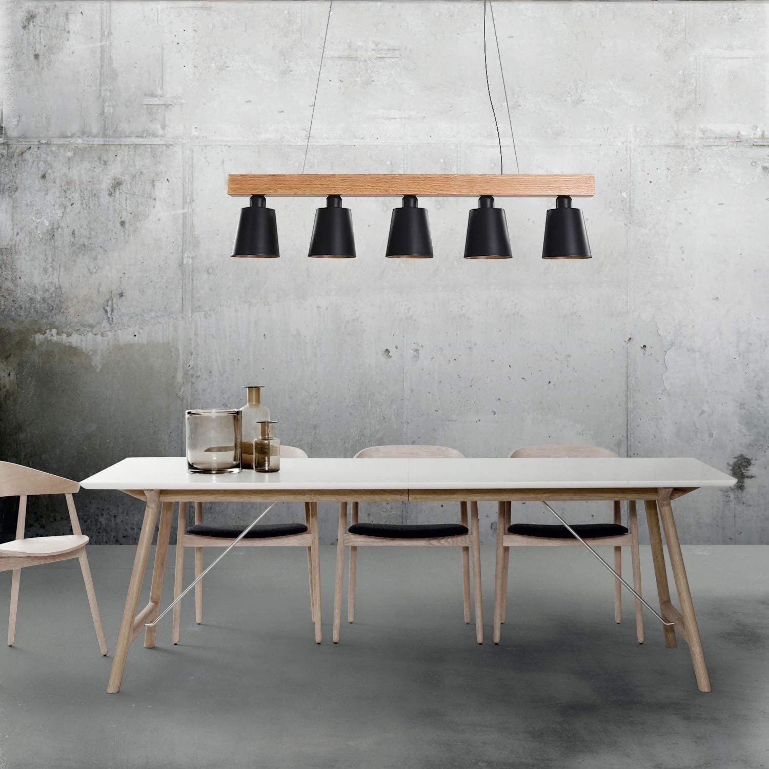 Stół jadalny z wiszącymi lampami. Lampy są czarne, a stół biały z drewnianymi krzesłami. Betonowe tło.