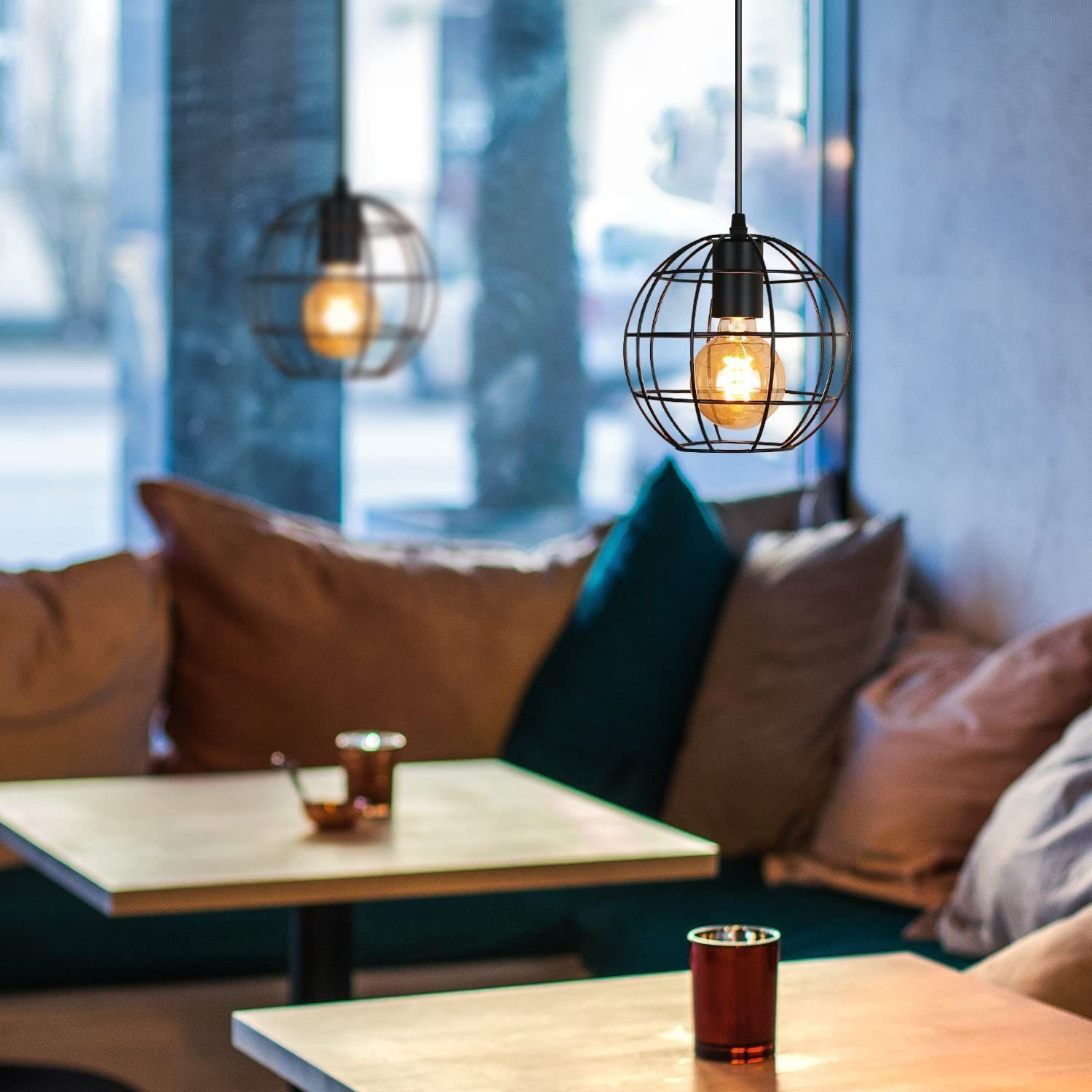 Dwie wiszące lampy w kształcie kuli z żarówkami Edisona, wiszące w kawiarni.