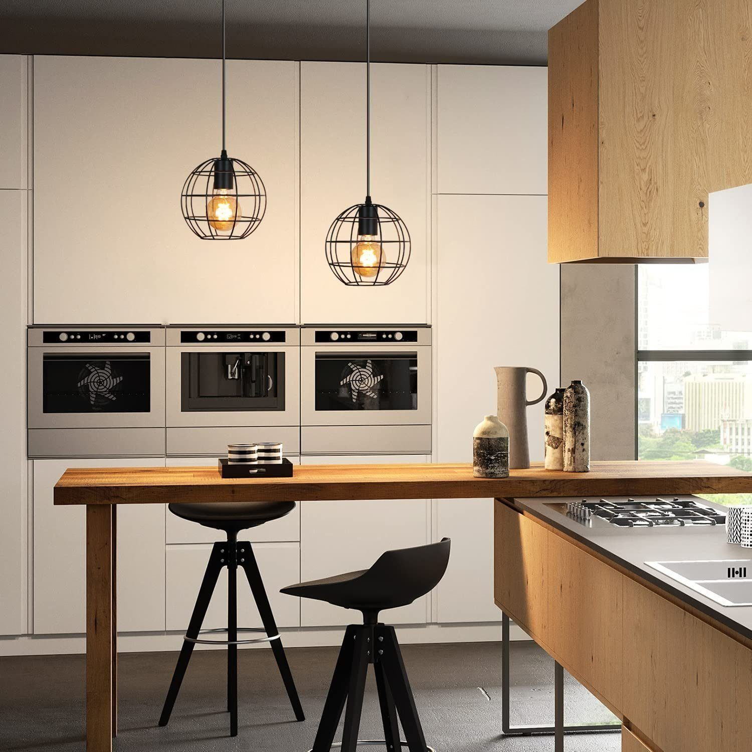 Dwie lampy wiszące z czarnymi metalowymi ramami i dekoracyjnymi żarówkami w nowoczesnej kuchni.