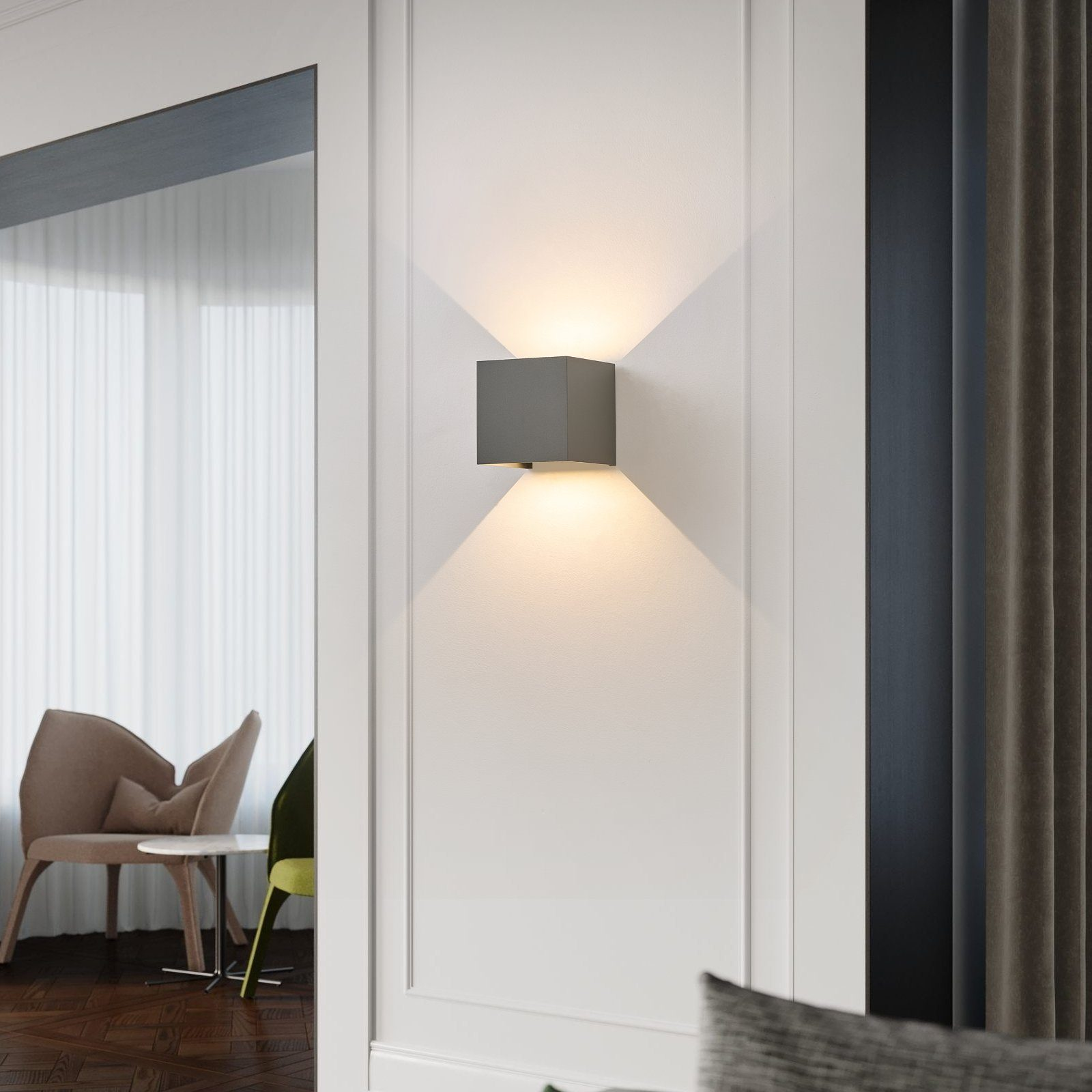 Una lampada da parete quadrata grigia con un muro bianco e una vista su una stanza con sedie e tende.