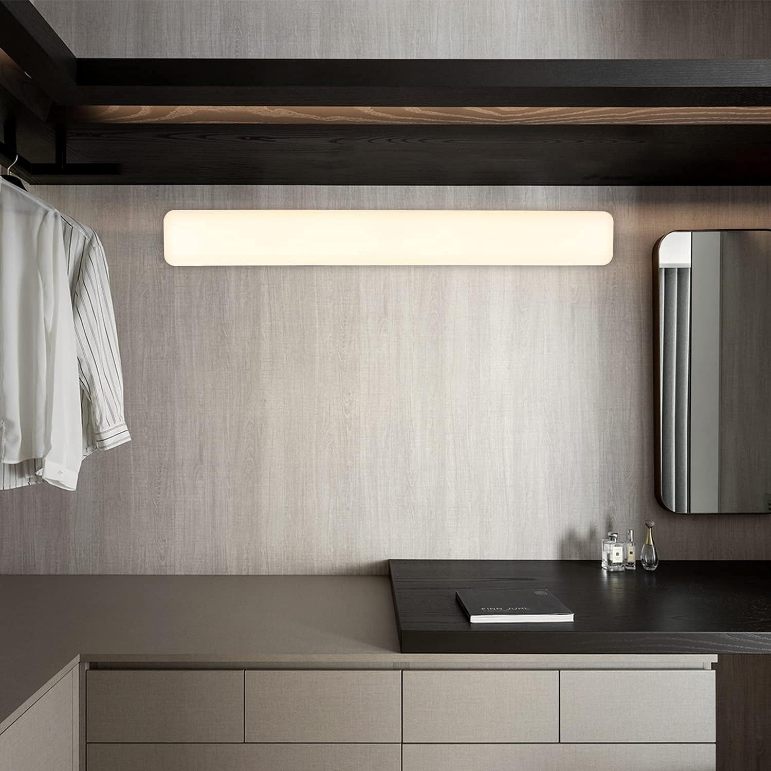 Długa, prostokątna oprawa oświetleniowa zamontowana na ścianie nad blatem i lustrem, we współczesnym wnętrzu.
