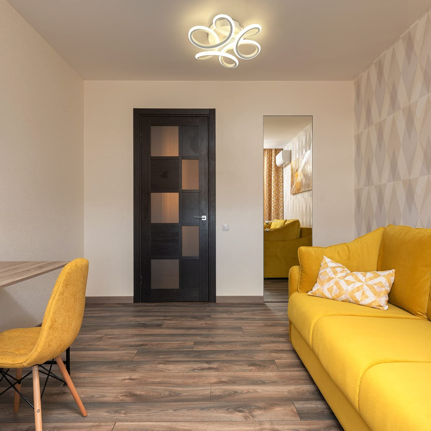 Pokój z żółtą sofą, krzesłem i ciemnymi drewnianymi drzwiami. Lampa na suficie.