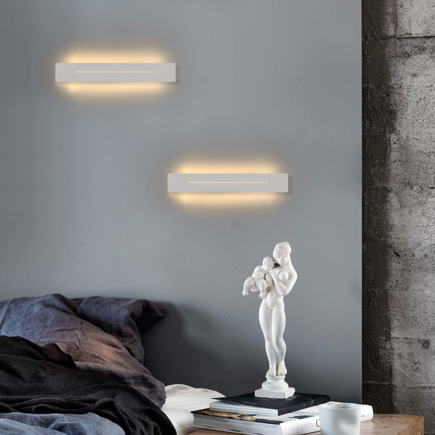 Dwie prostokątne lampy ścienne są włączone. Na stole stoi posąg kobiety trzymającej dziecko.