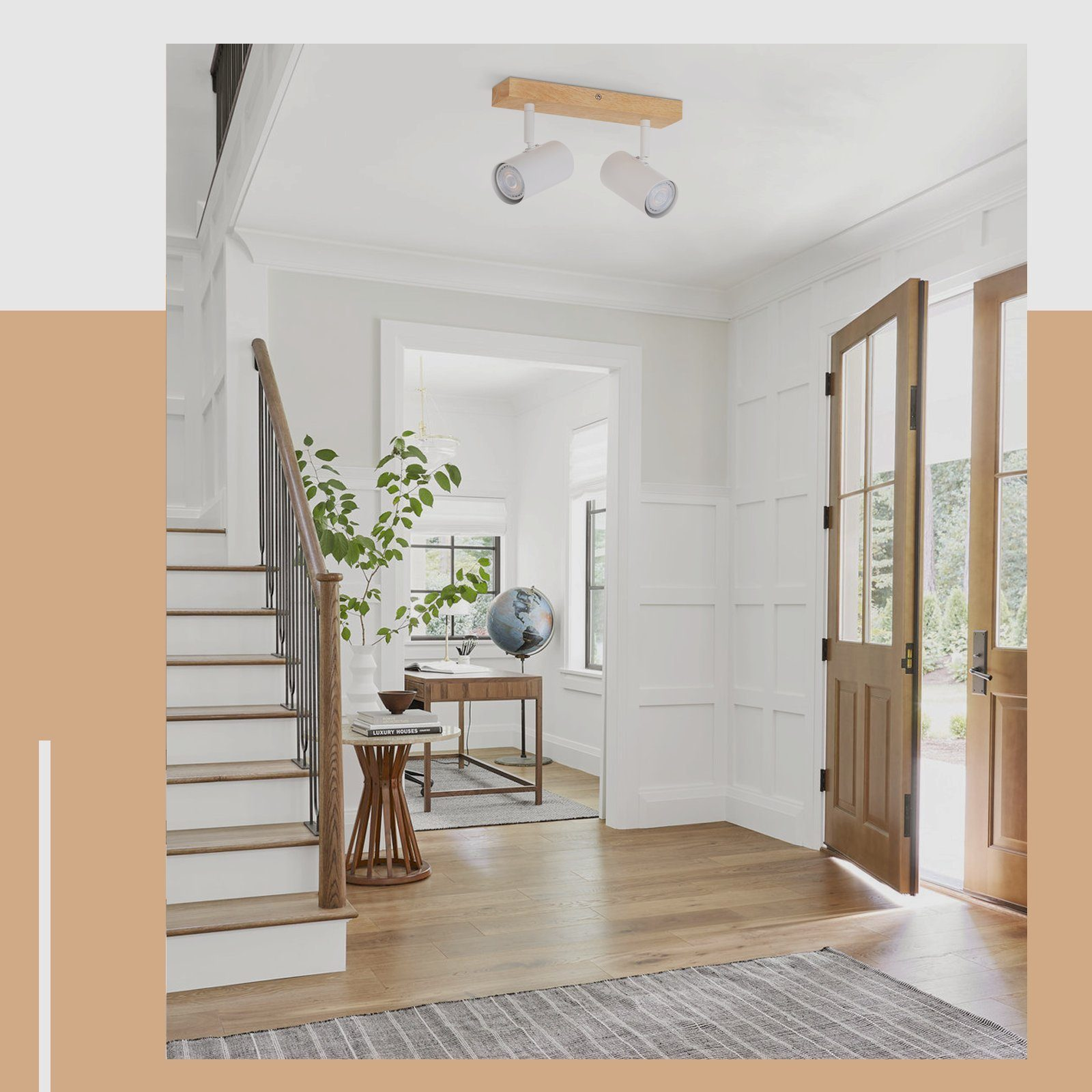 Hol z schodami, drewniana podłoga. Dwa białe reflektory na drewnianej belce, otwarte drzwi.