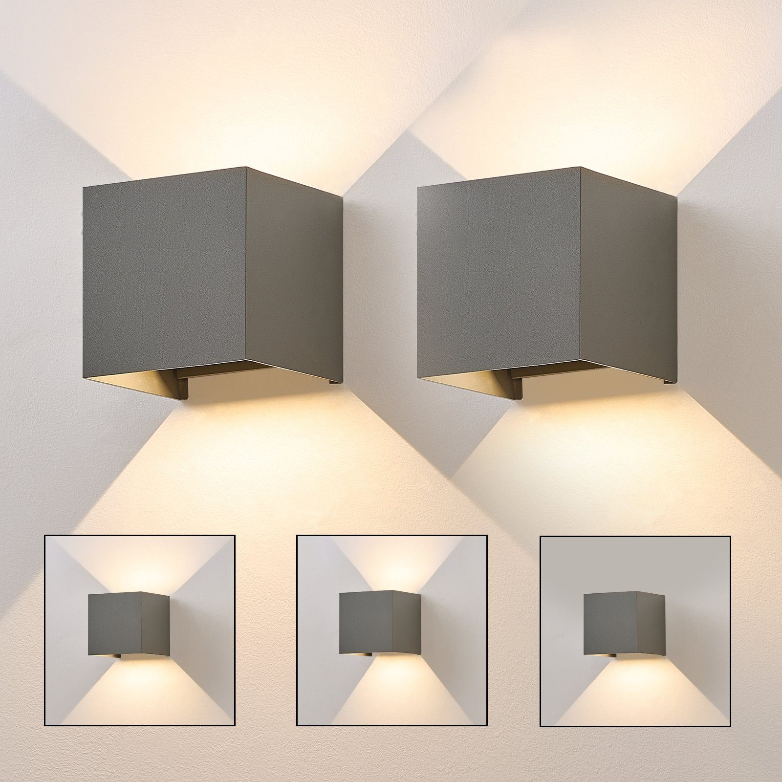 Dwie szare, sześcienne lampy ścienne z jasnym światłem świecącym w dół. Białe tło ściany.