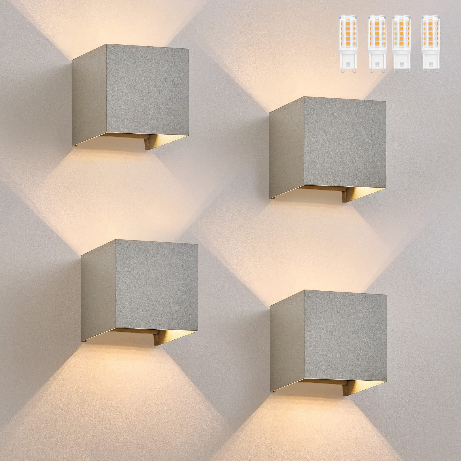 Cztery szare lampy ścienne w kształcie kostki z pomarańczowym światłem świecącym w dół.