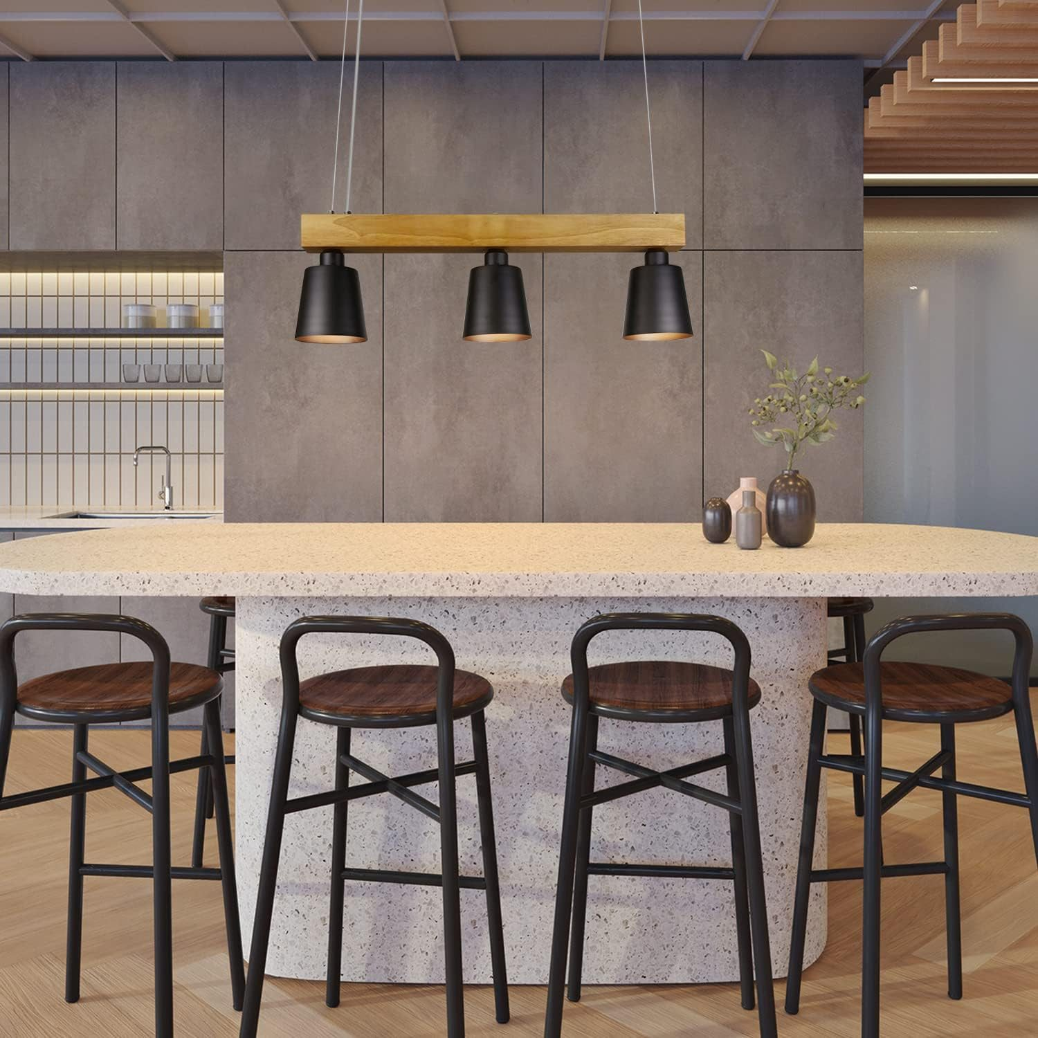 Una cucina con una trave in legno chiaro che sorregge tre luci a sospensione nere sopra un bar.