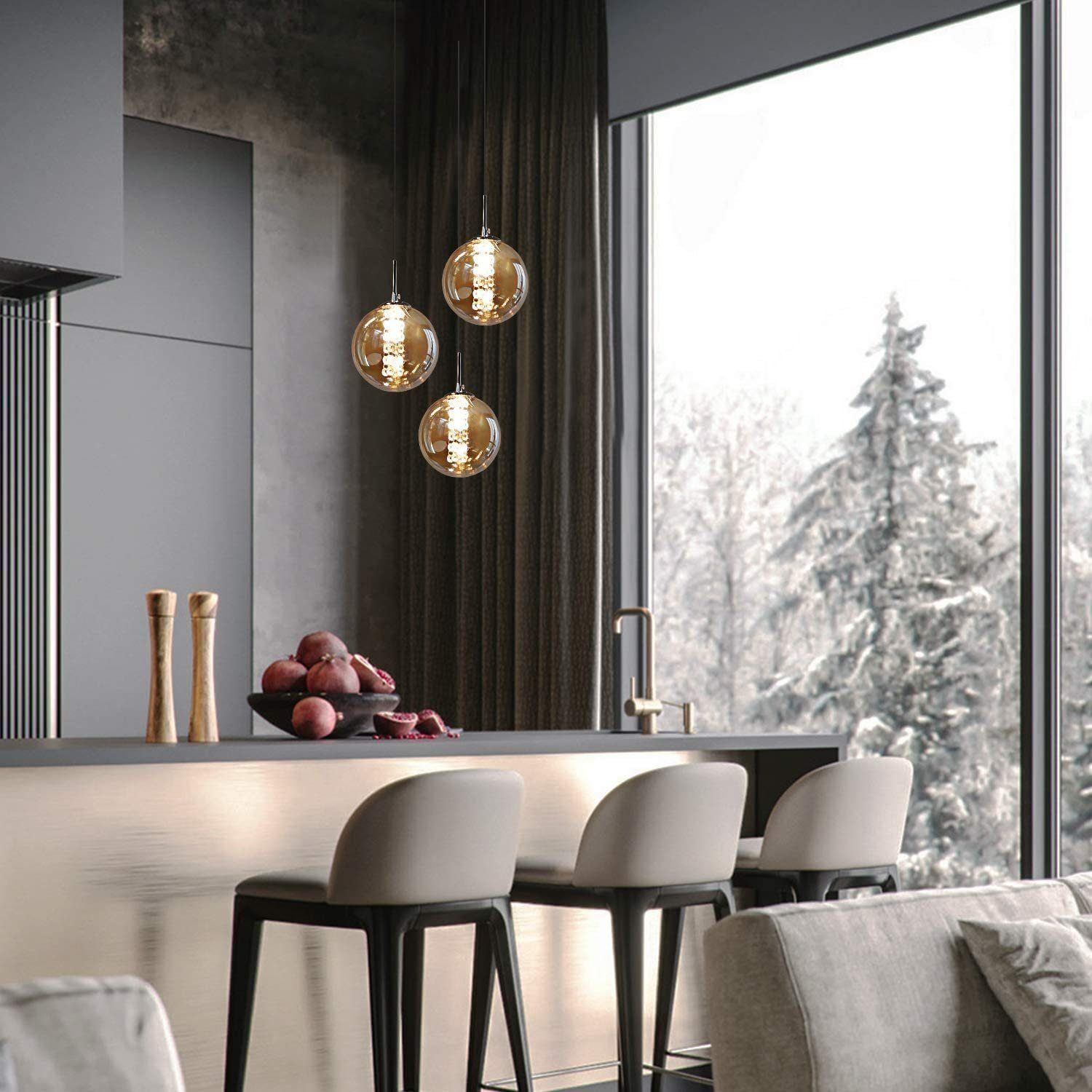 Scena kuchenna z trzema wiszącymi lampami kulistymi. Przez duże okno widać zaśnieżony widok na zewnątrz.