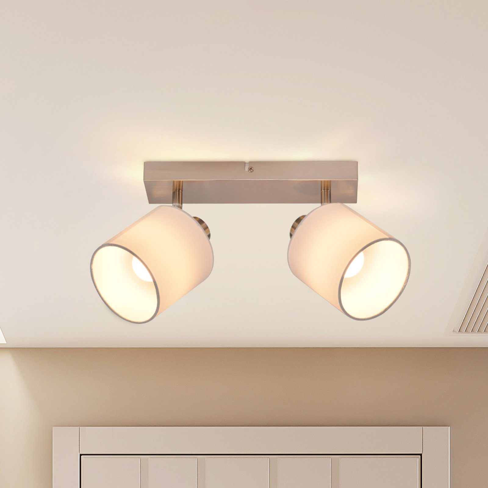 Dwie białe lampy przymocowane do prostokątnej srebrnej listwy. Lampy skierowane w dół, na białym tle.