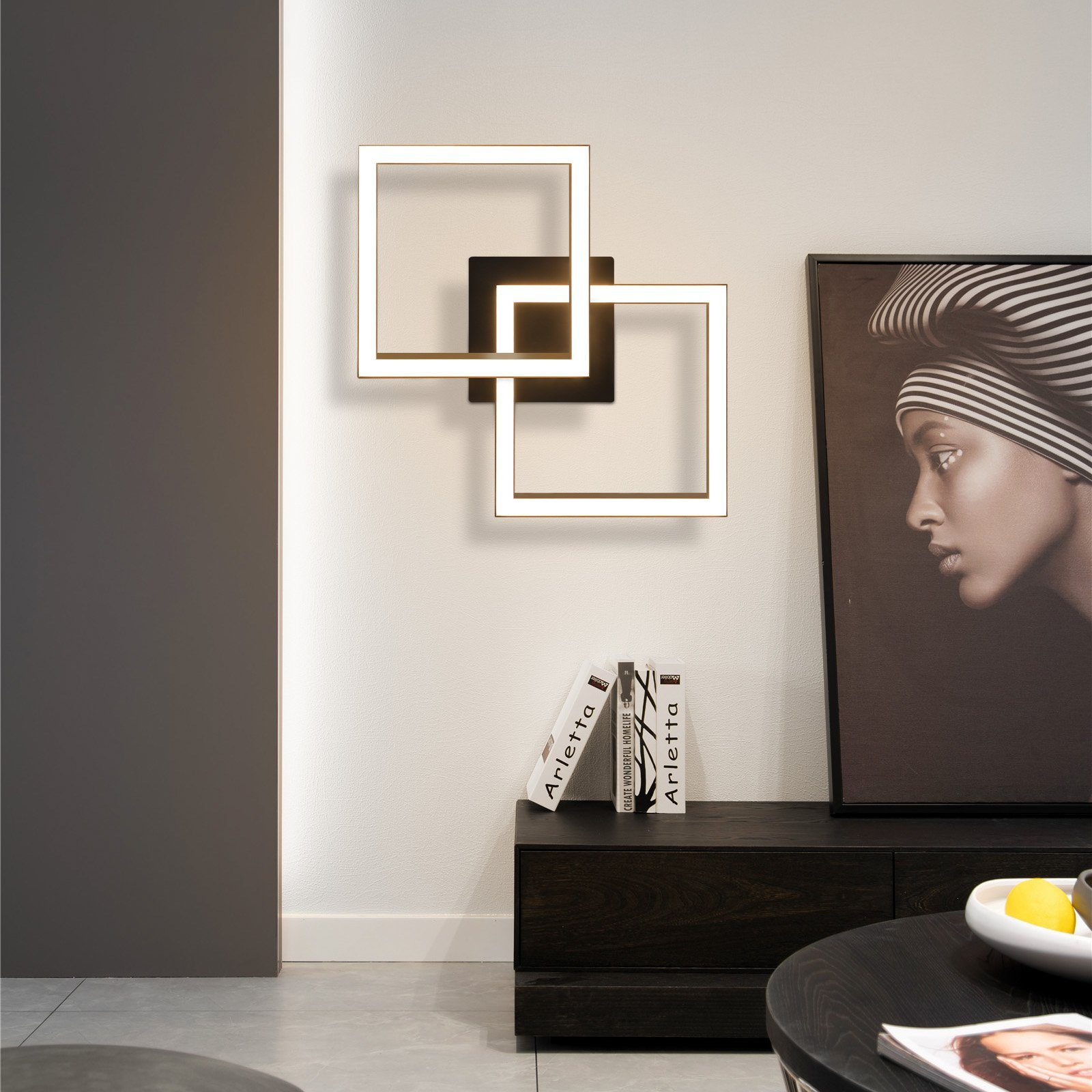 Nowoczesna lampa ścienna wykonana z trzech kwadratów. Portret kobiety na ścianie. Stół na pierwszym planie.