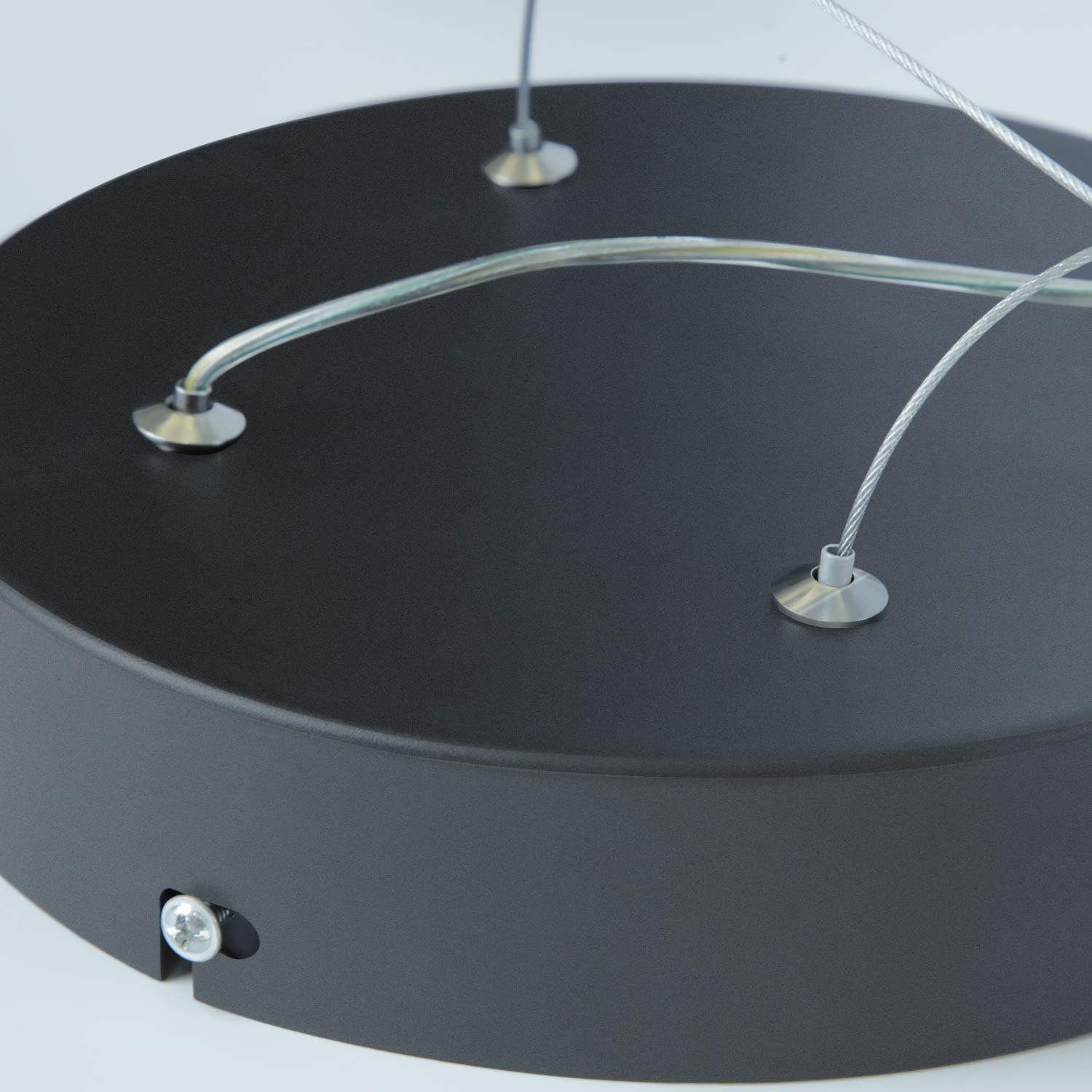 Zbliżenie na czarną okrągłą podstawę lampy z trzema metalowymi kablami.