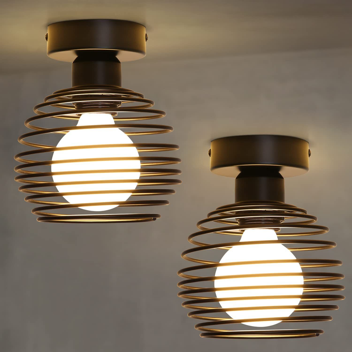Dwie lampy sufitowe z kulistymi metalowymi klatkami, każda z centralną żarówką.