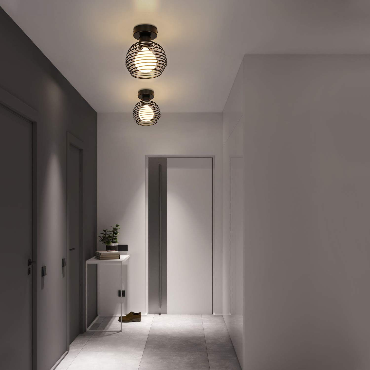 Dwie czarne, druciane lampy kuliste wiszące w korytarzu. Jest białe drzwi i stół.