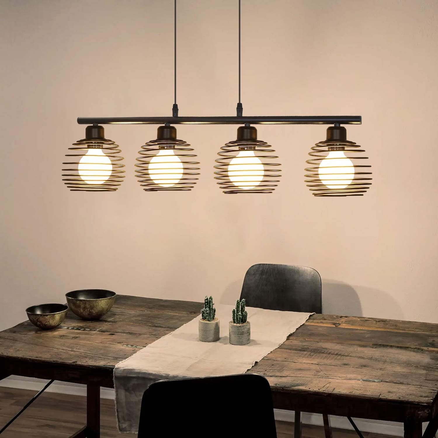 Jadalnia ze stołem drewnianym, czarnymi krzesłami i czterema wiszącymi oprawami oświetleniowymi z drucianą klatką.