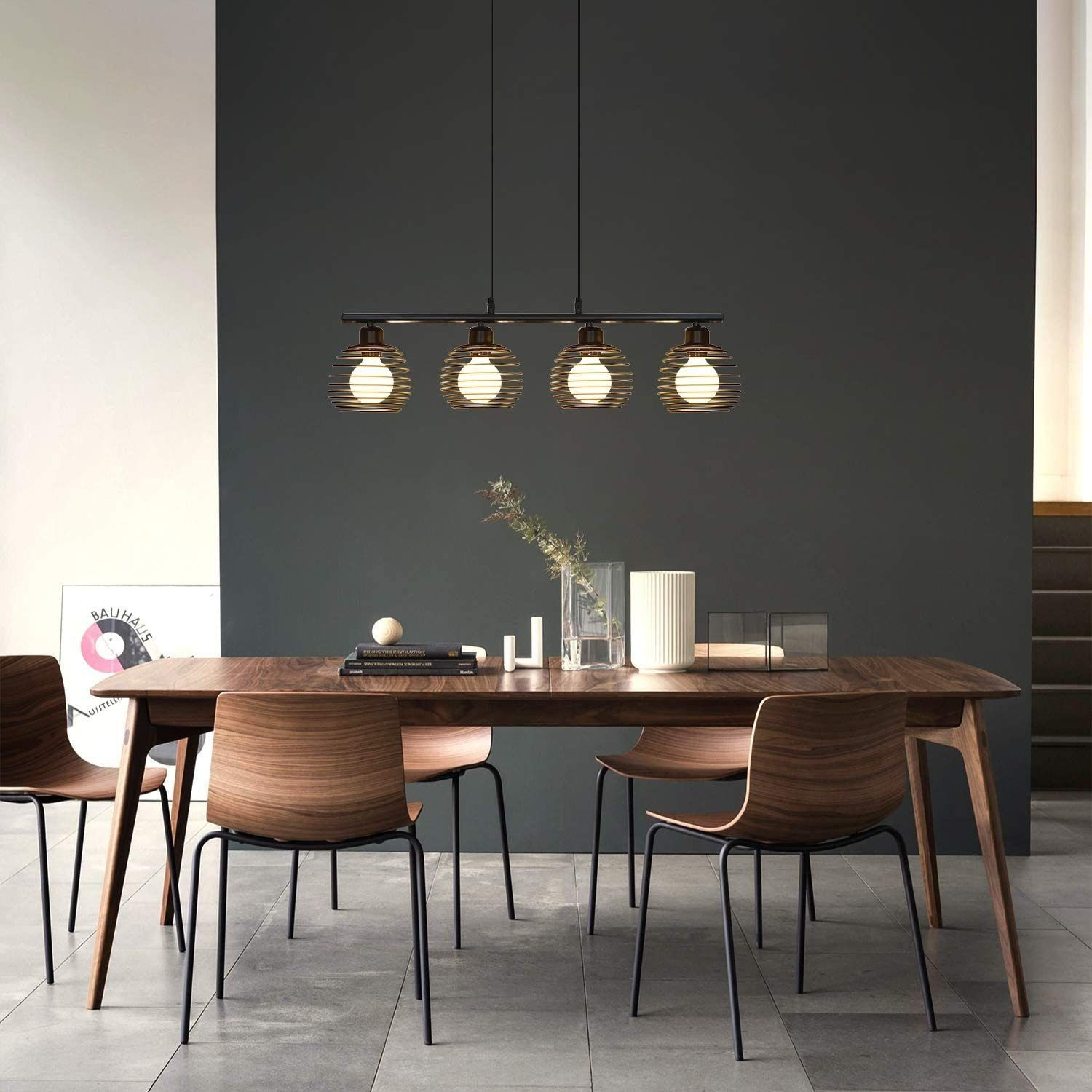 Jadalnia z długim drewnianym stołem. Cztery krzesła, wazon i lampa są widoczne.