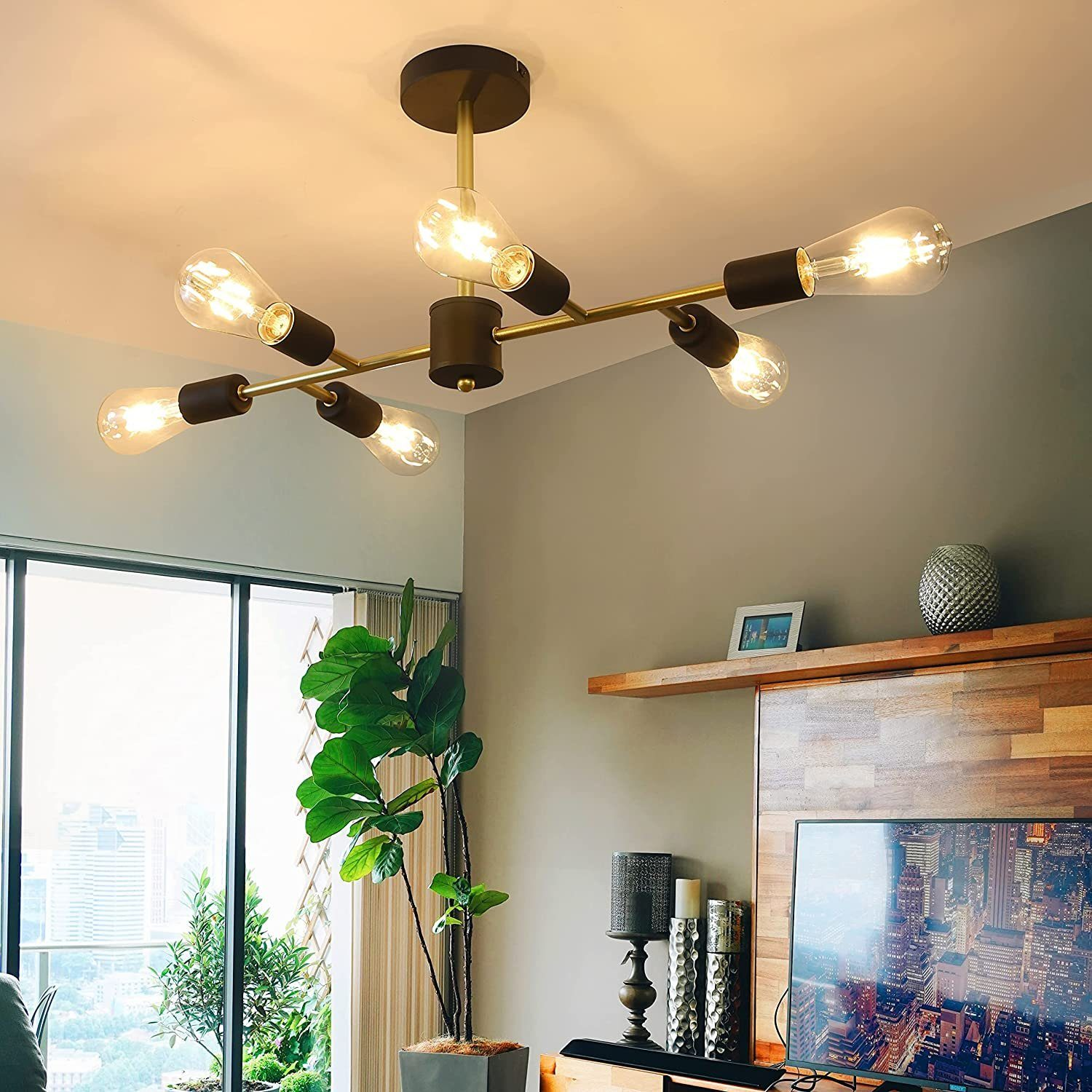 Salon z nowoczesnym żyrandolem i dużą rośliną doniczkową.